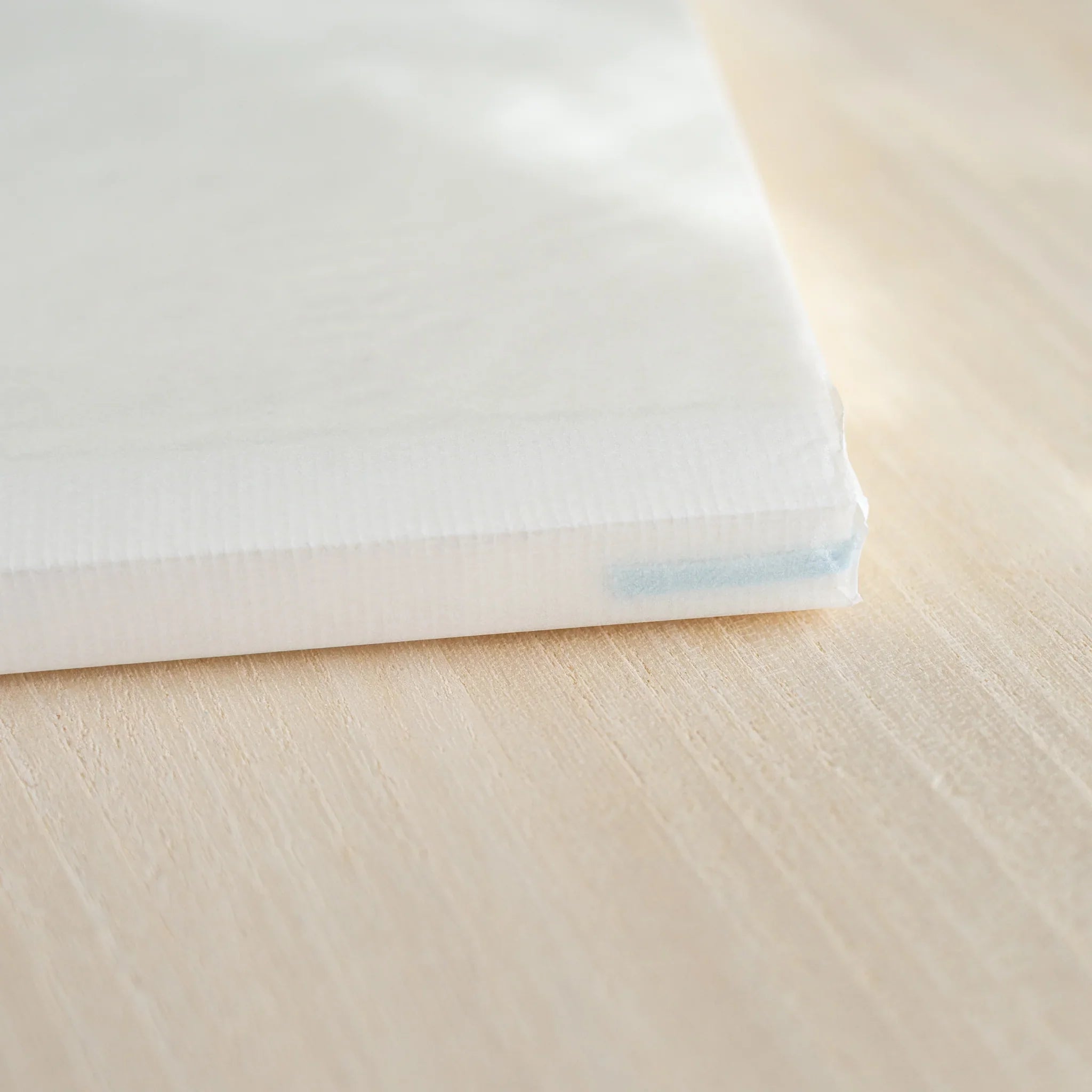 Closed Midori MD Notebook A5, angled view showing white linen cover, ivory page edges, and blue ribbon bookmark at corner