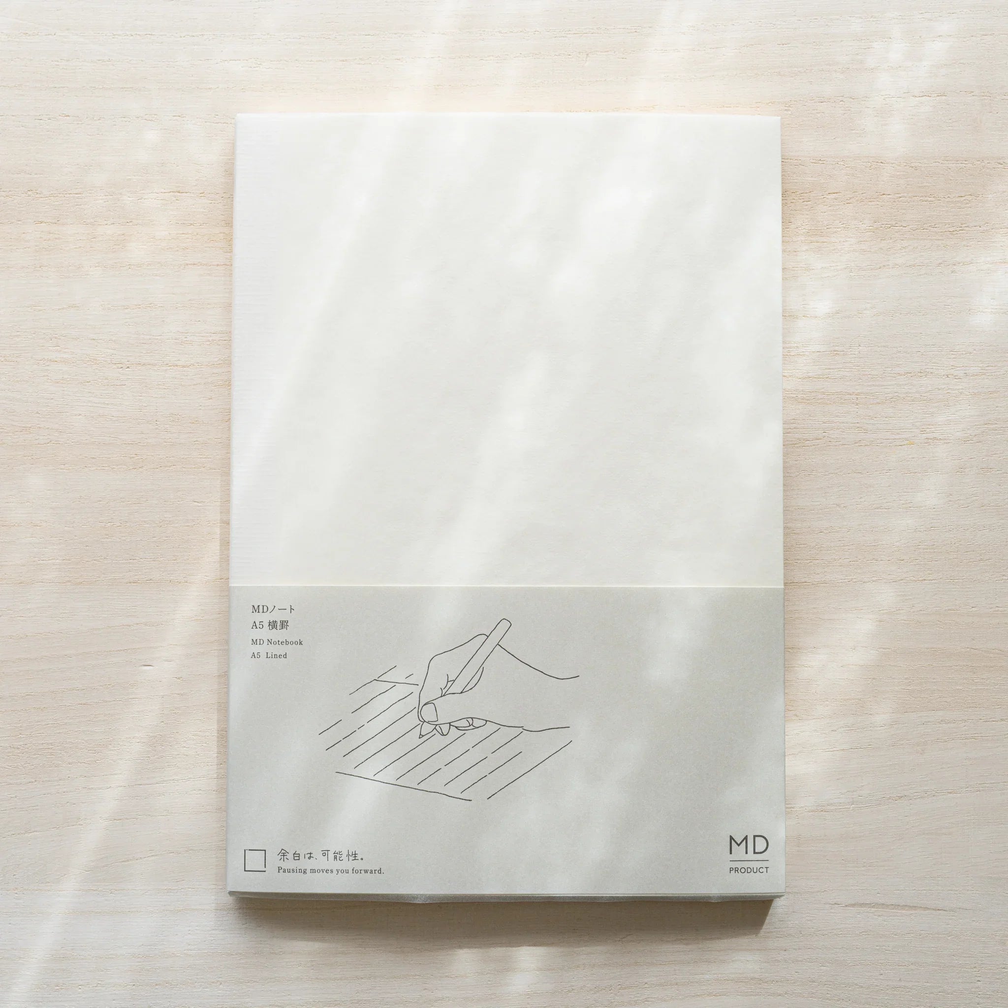 Midori MD Notebook A5 Lined belly band with gray line illustration of hand writing on lines, text MD Notebook A5 Lined