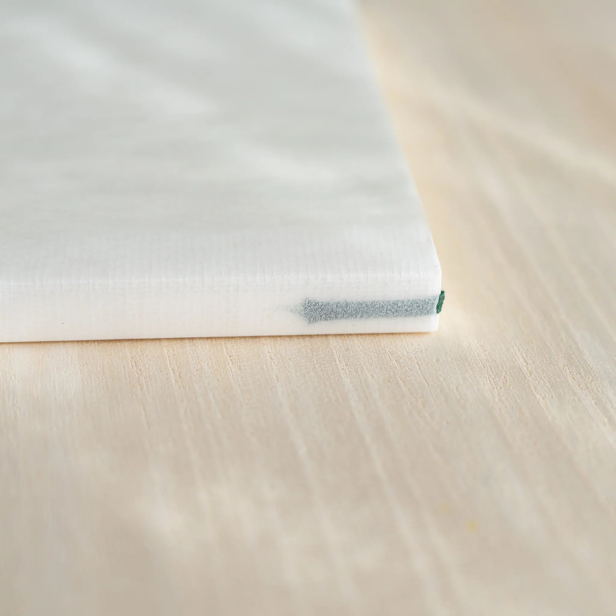 Close-up of Midori MD Notebook A5 spine corner showing ivory page stack, thread-stitched binding, and dark green ribbon