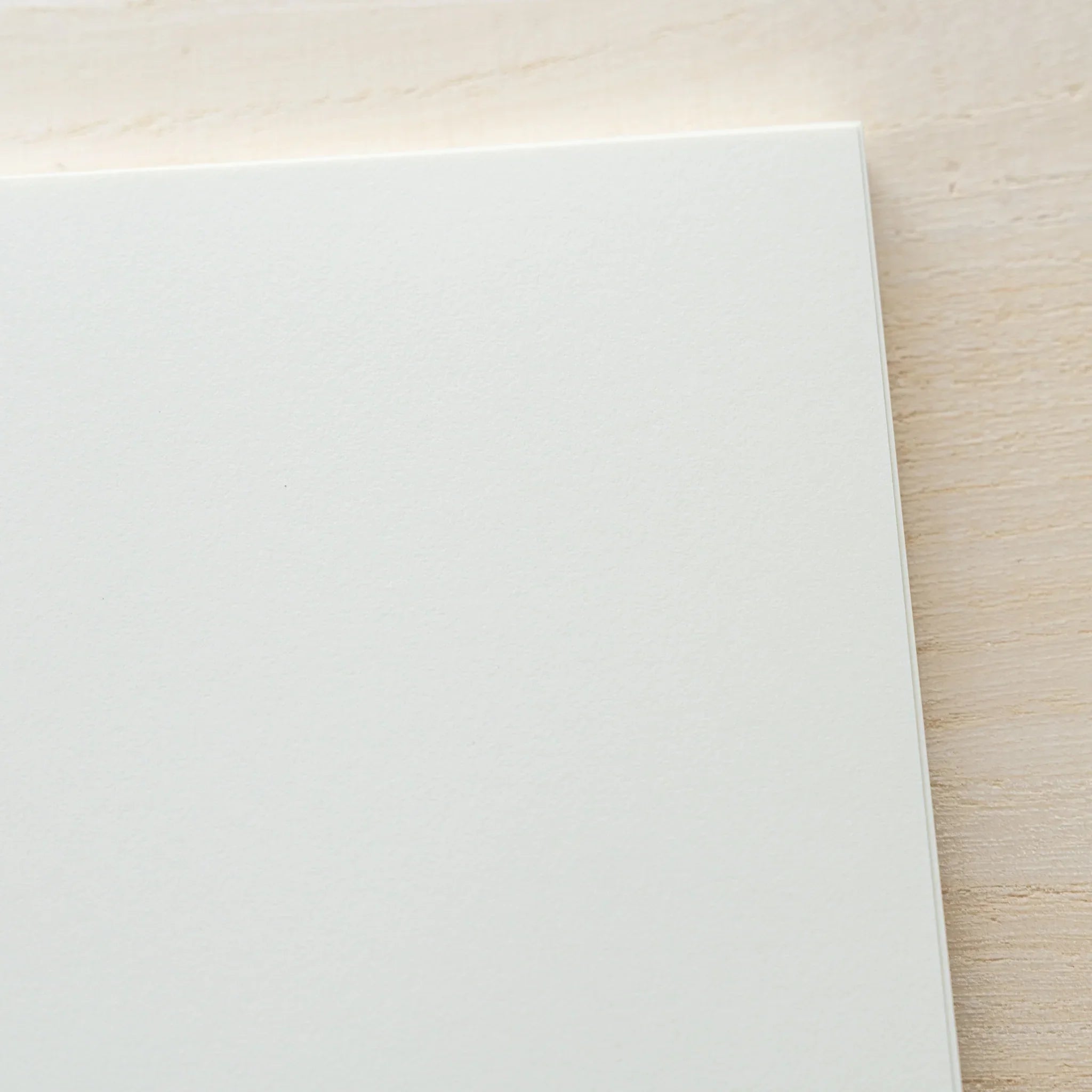 Midori MD Notebook A5 blank ivory page close-up showing smooth paper surface texture and rounded corner on wood