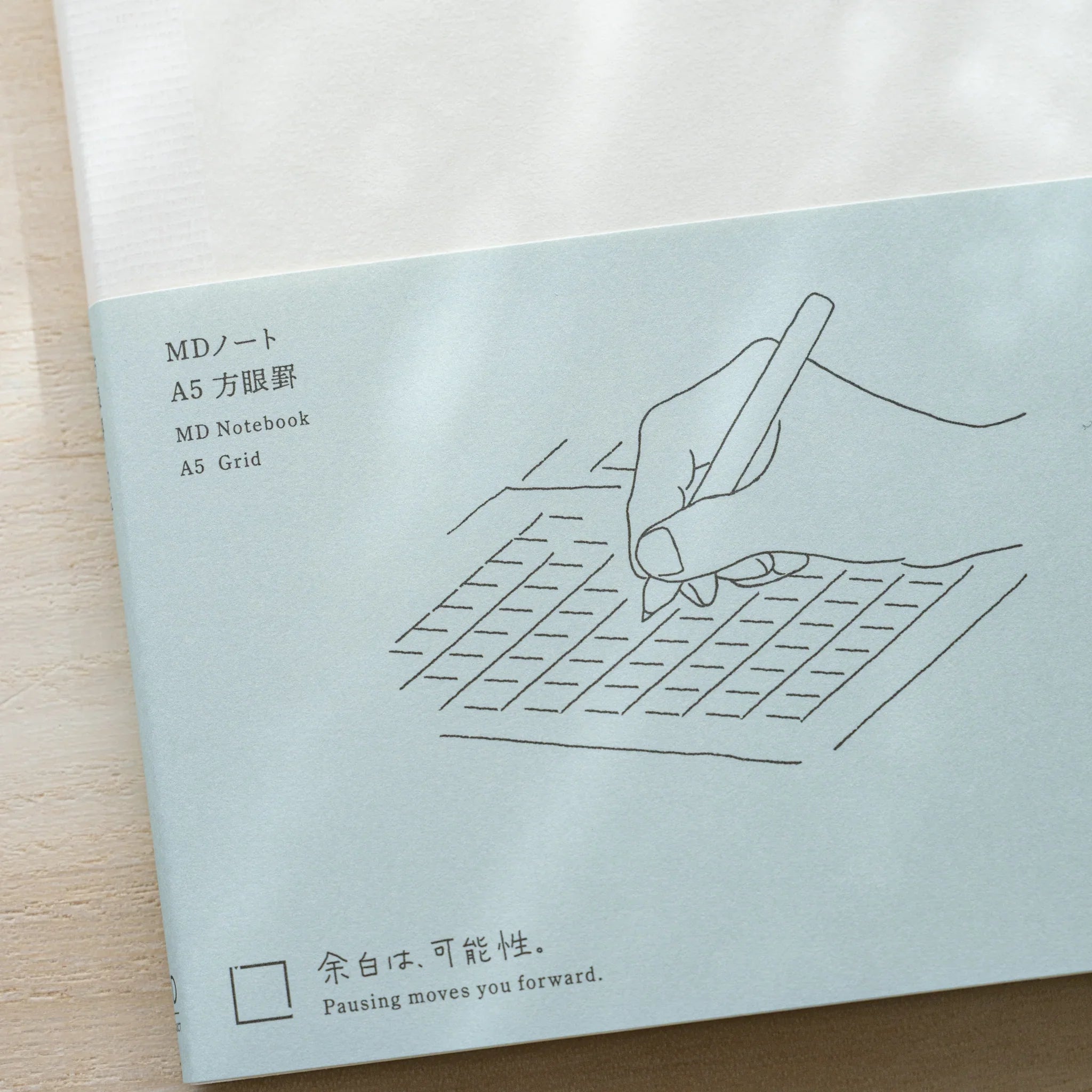 Close-up of Midori MD Notebook A5 Grid belly band showing hand writing illustration, MD Notebook A5 Grid text and tagline
