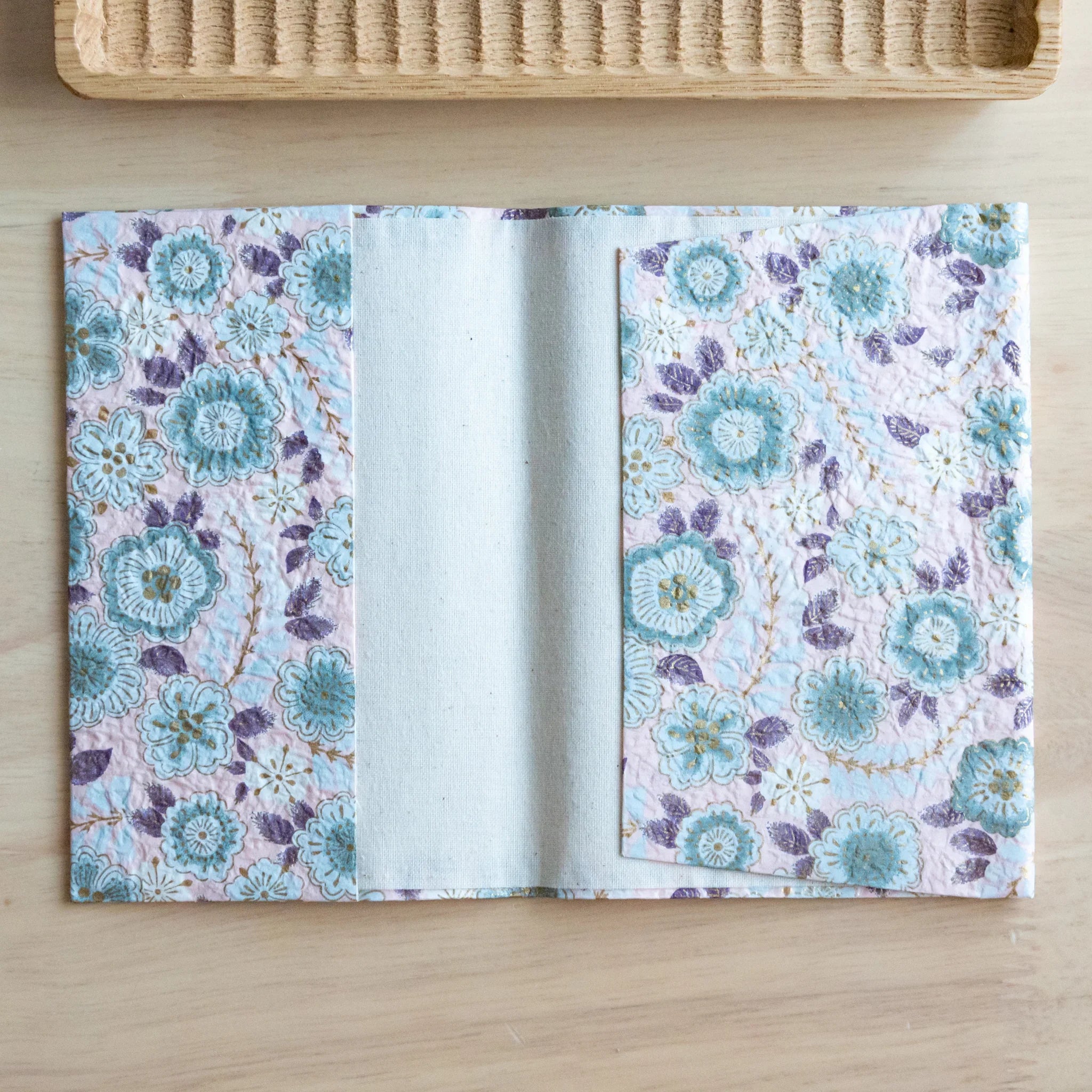 Pastel pink hand-dyed yuzen washi book cover unfolded flat showing turquoise and purple floral print.
