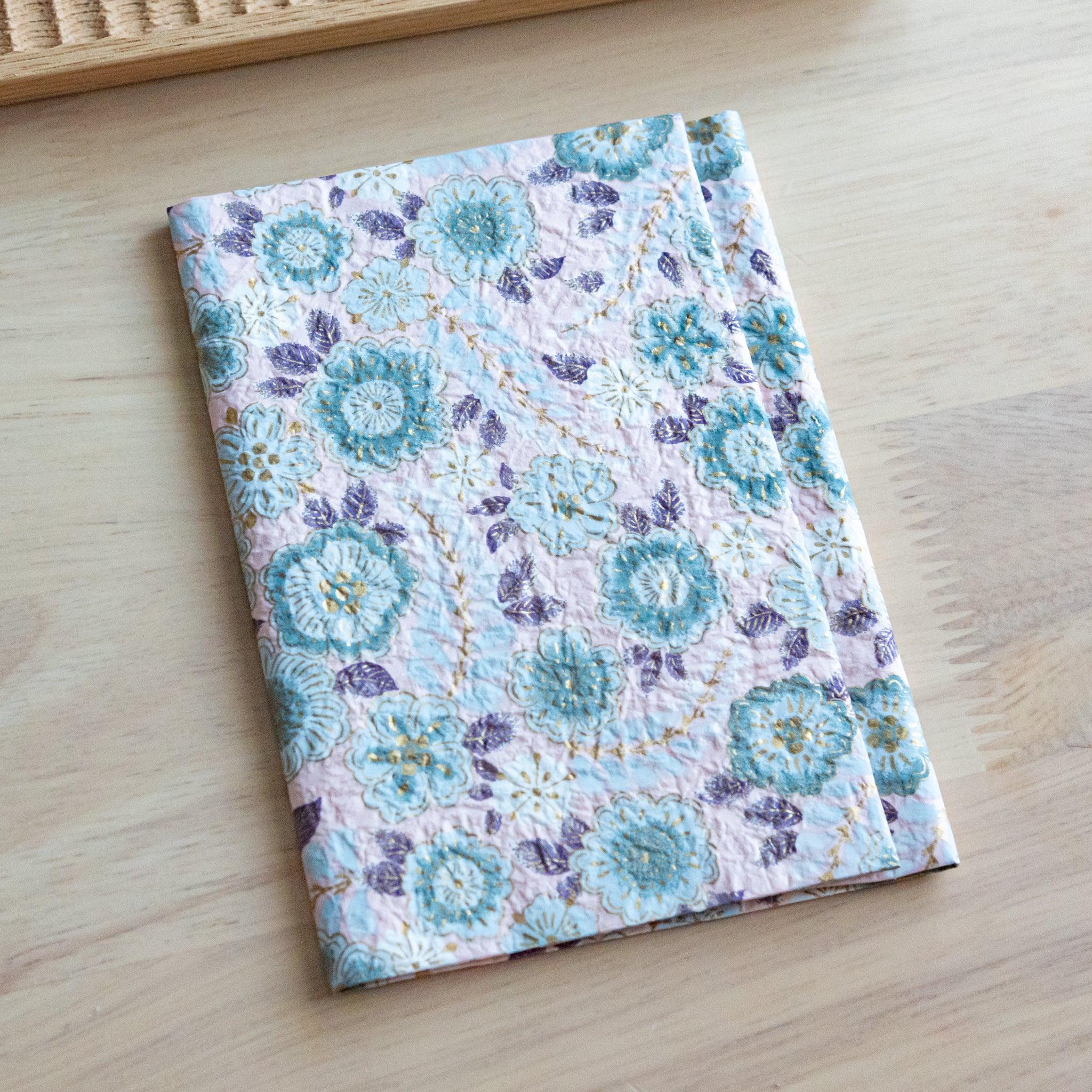 Pastel pink hand-dyed yuzen washi book cover A6, flat lay composition on light wood highlighting floral motif hue
