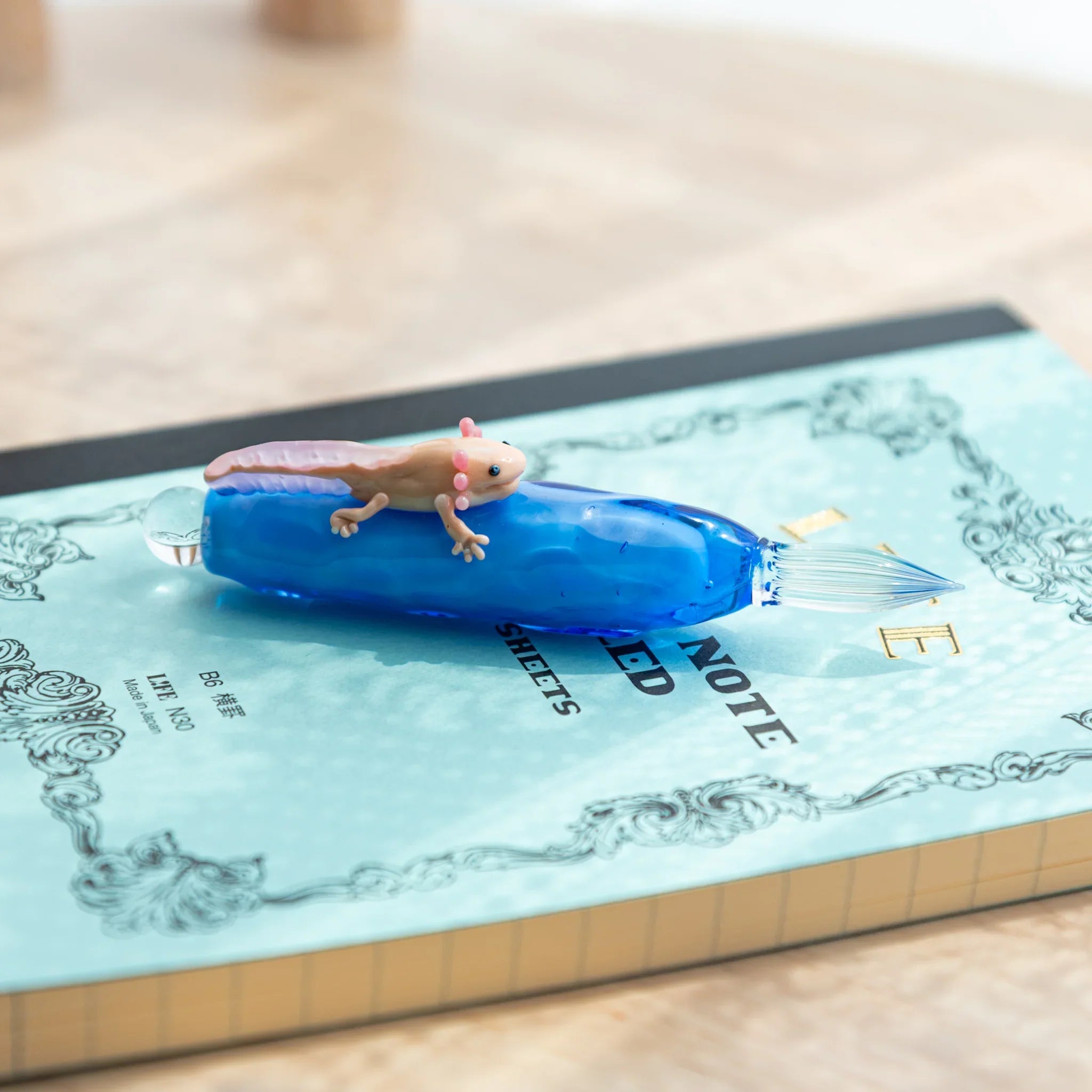 Floating axolotl glass dip pen featuring adorable pink creature for creative writing with unique design