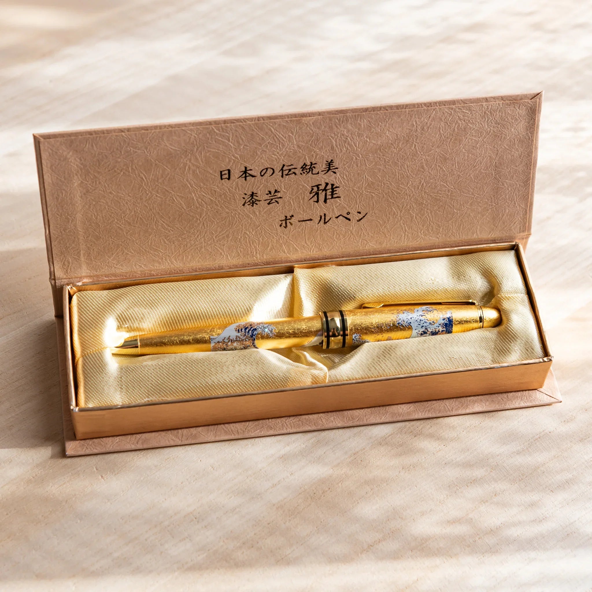 Gold Leaf Great Wave Japanese Ballpoint Pen displayed in a satin-lined gift box, showing its gold body and blue wave art.