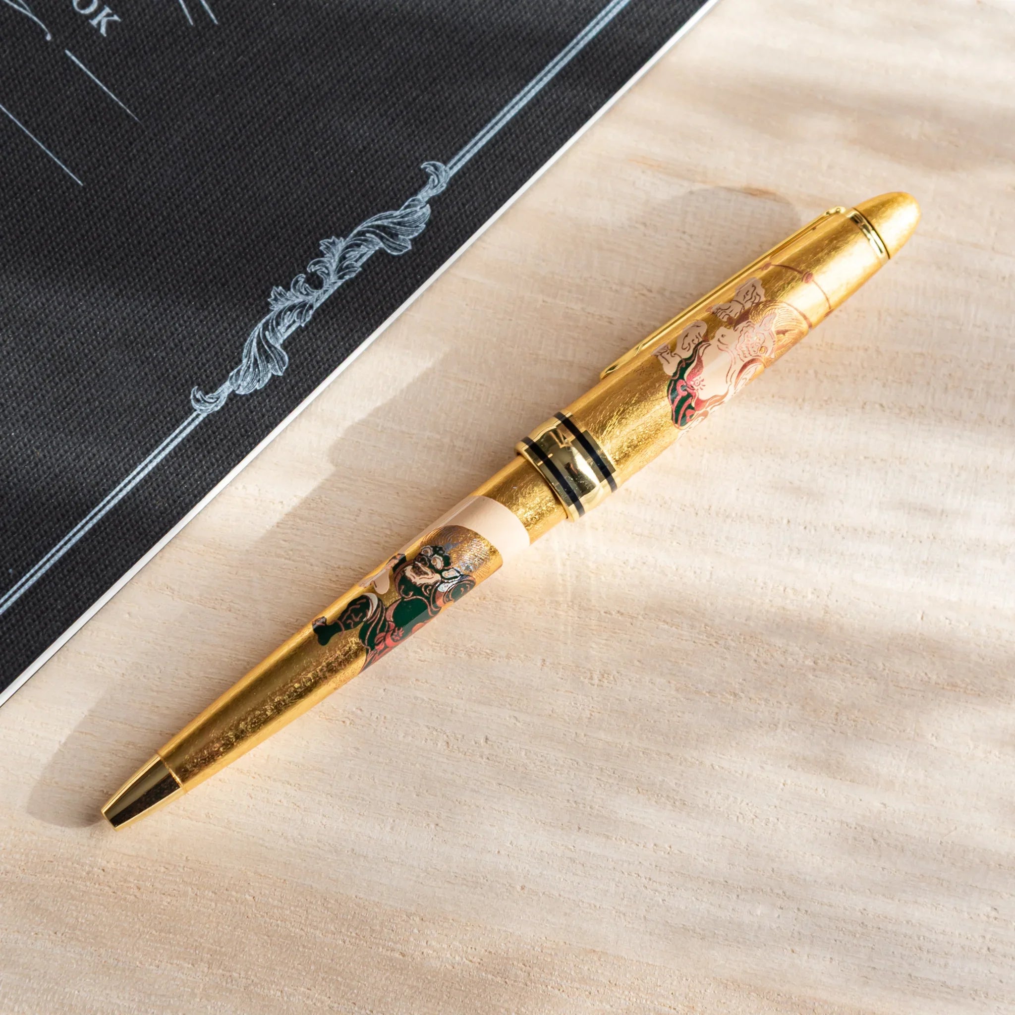 Gold Leaf Gods of Wind and Thunder ballpoint pen with black barrel and gold accent trim displayed clearly