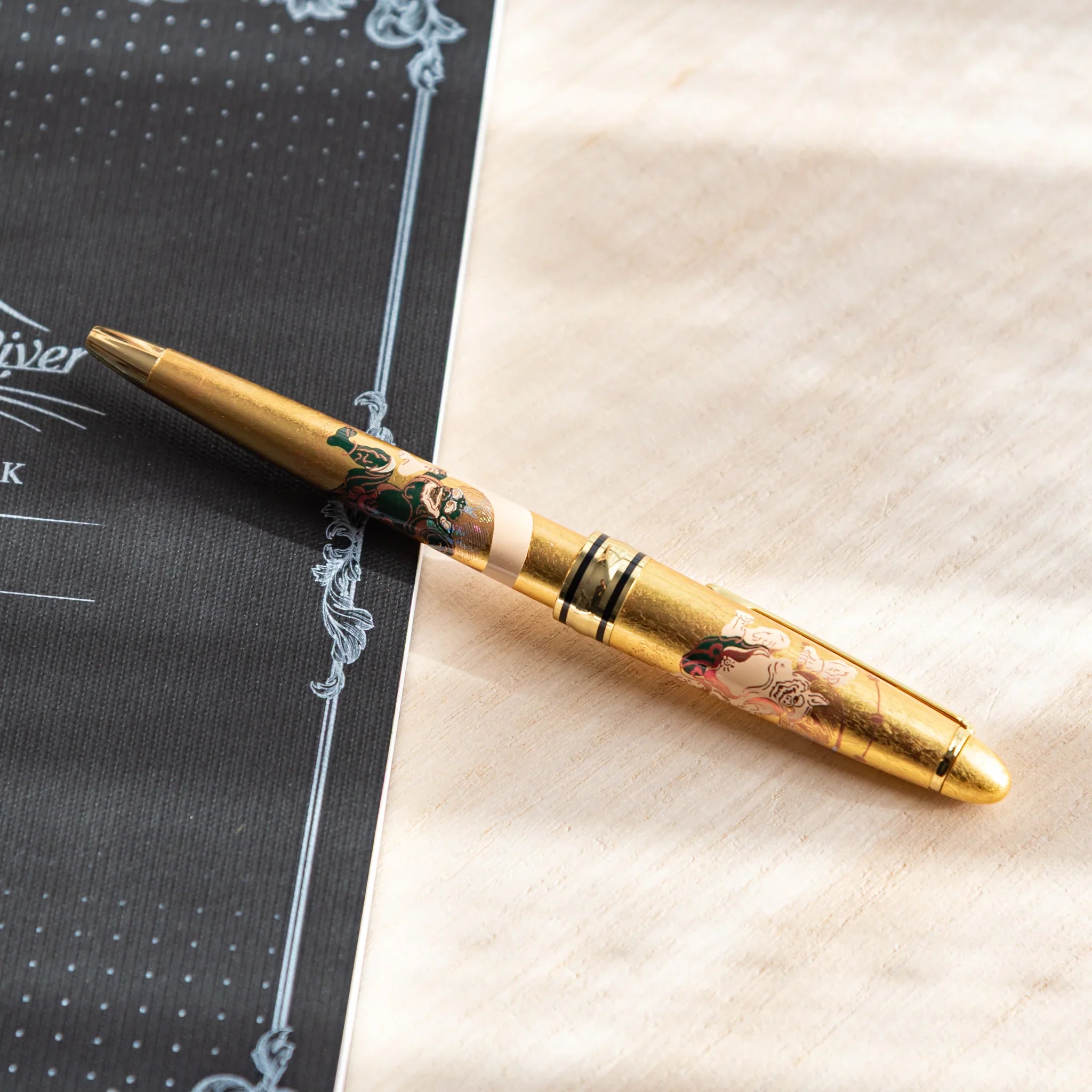Ballpoint pen with gold leaf decoration showing wind and thunder deity motif design displayed clearly