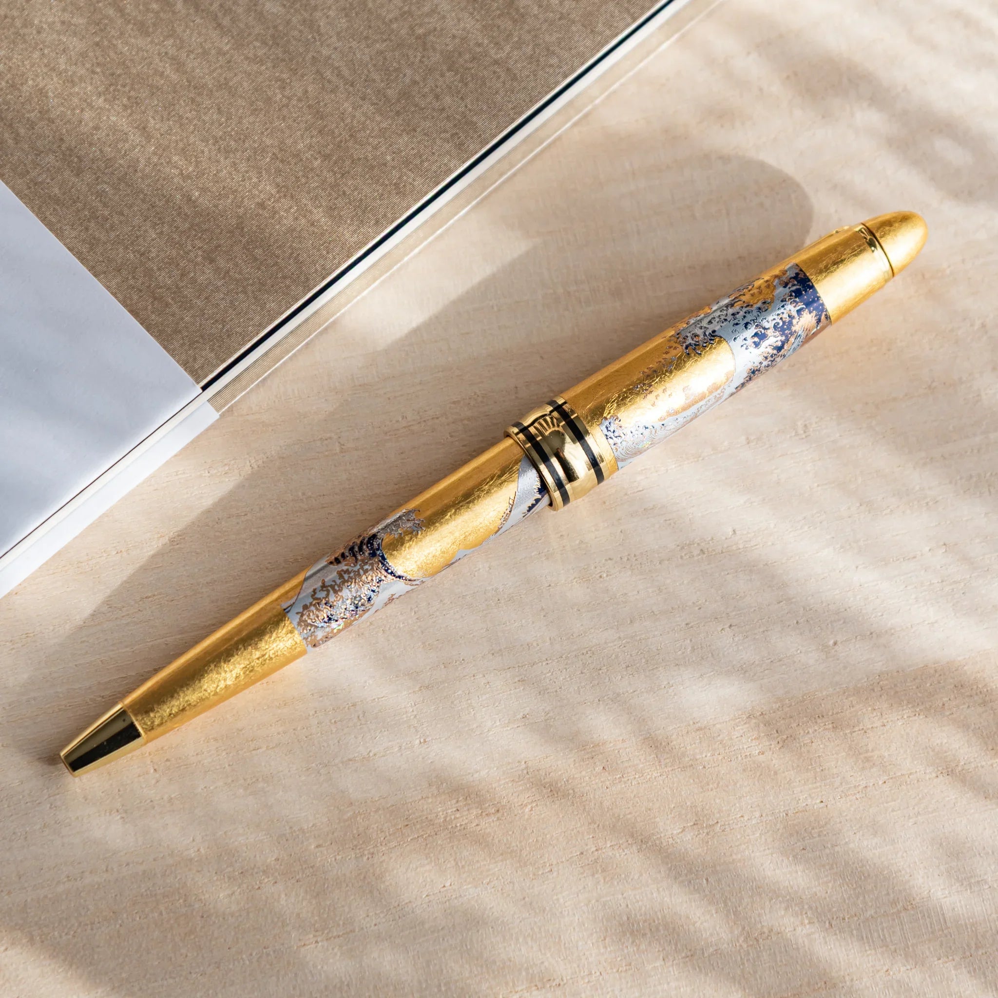 Gold Leaf Great Wave Hokusai ballpoint pen with black barrel and gold accent trim displayed clearly composition
