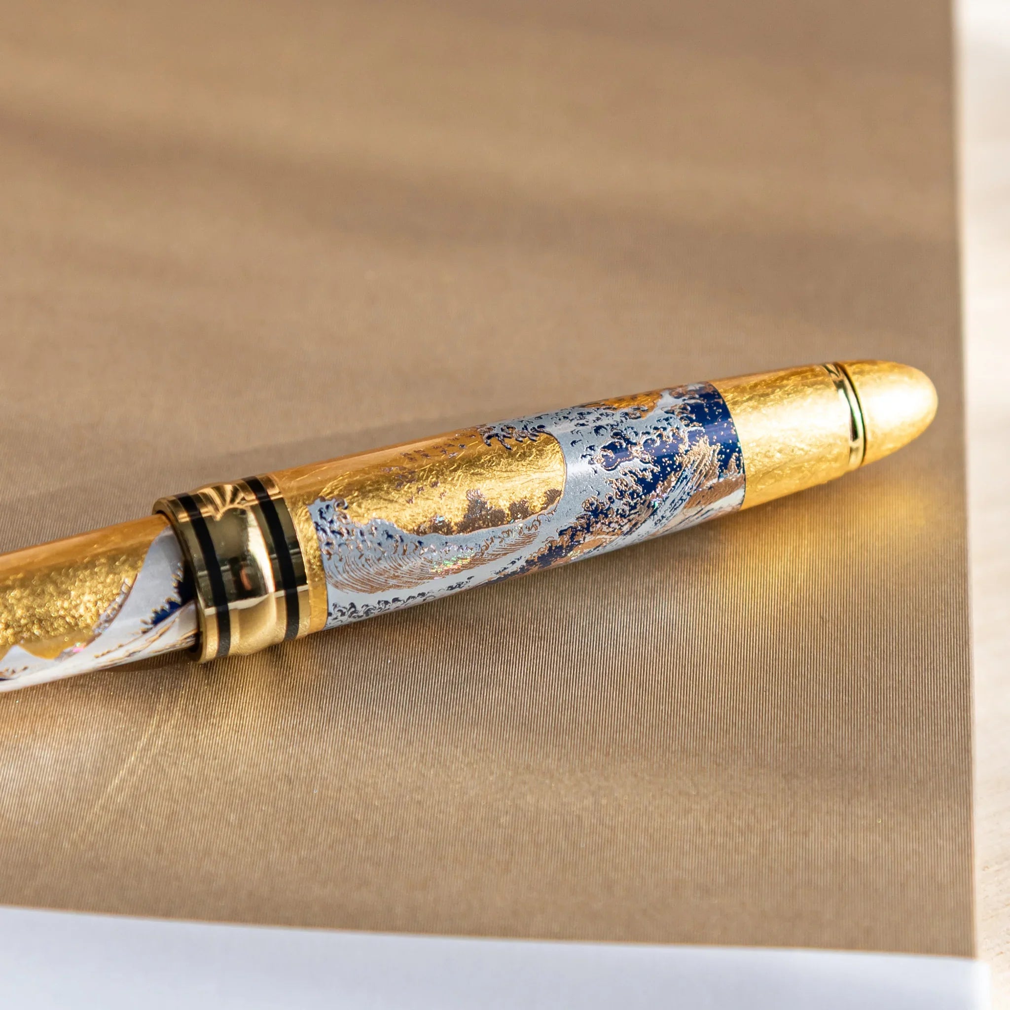 Black ballpoint pen with gold trim showing Great Wave landscape composition design displayed clearly