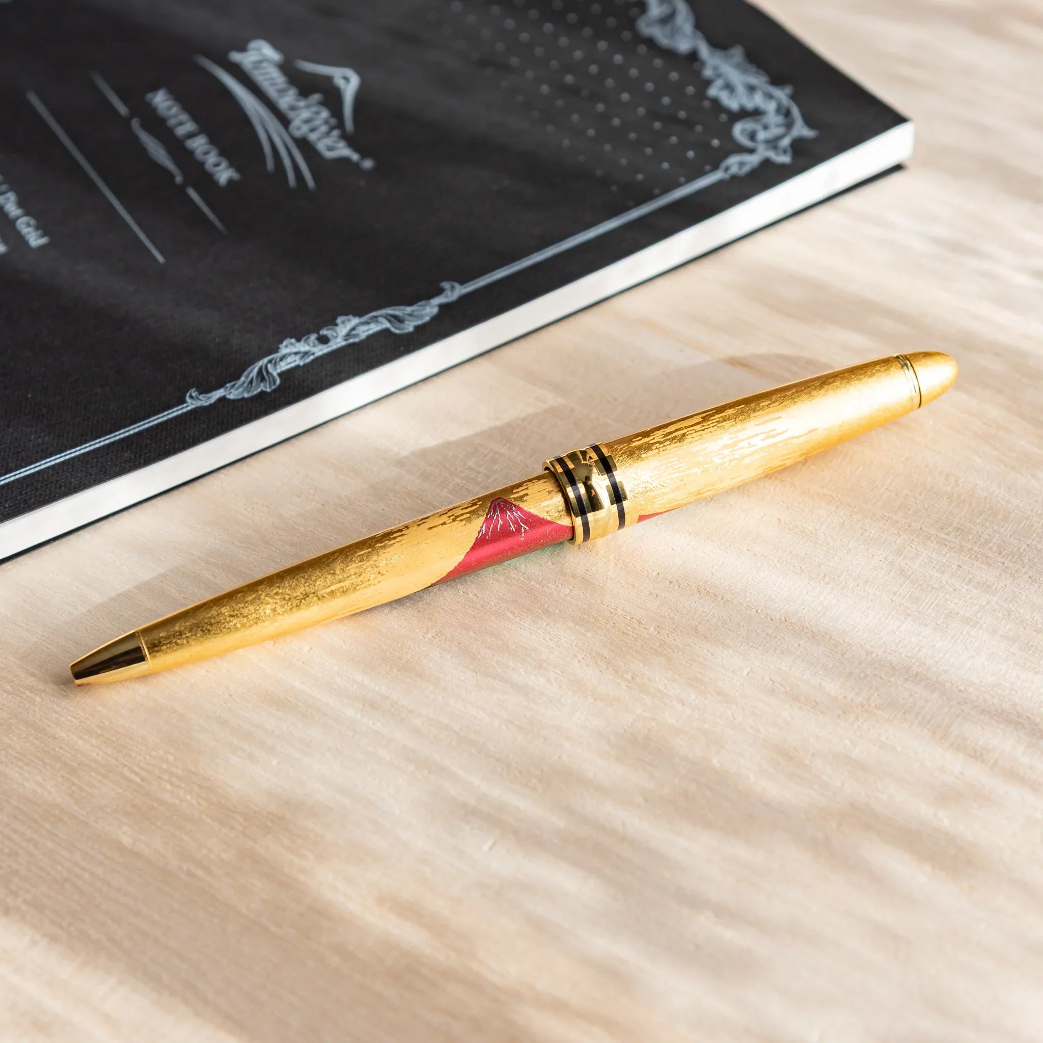 Gold Leaf Mt. Fuji ballpoint pen with black barrel and gold accent trim detail and composition in composition