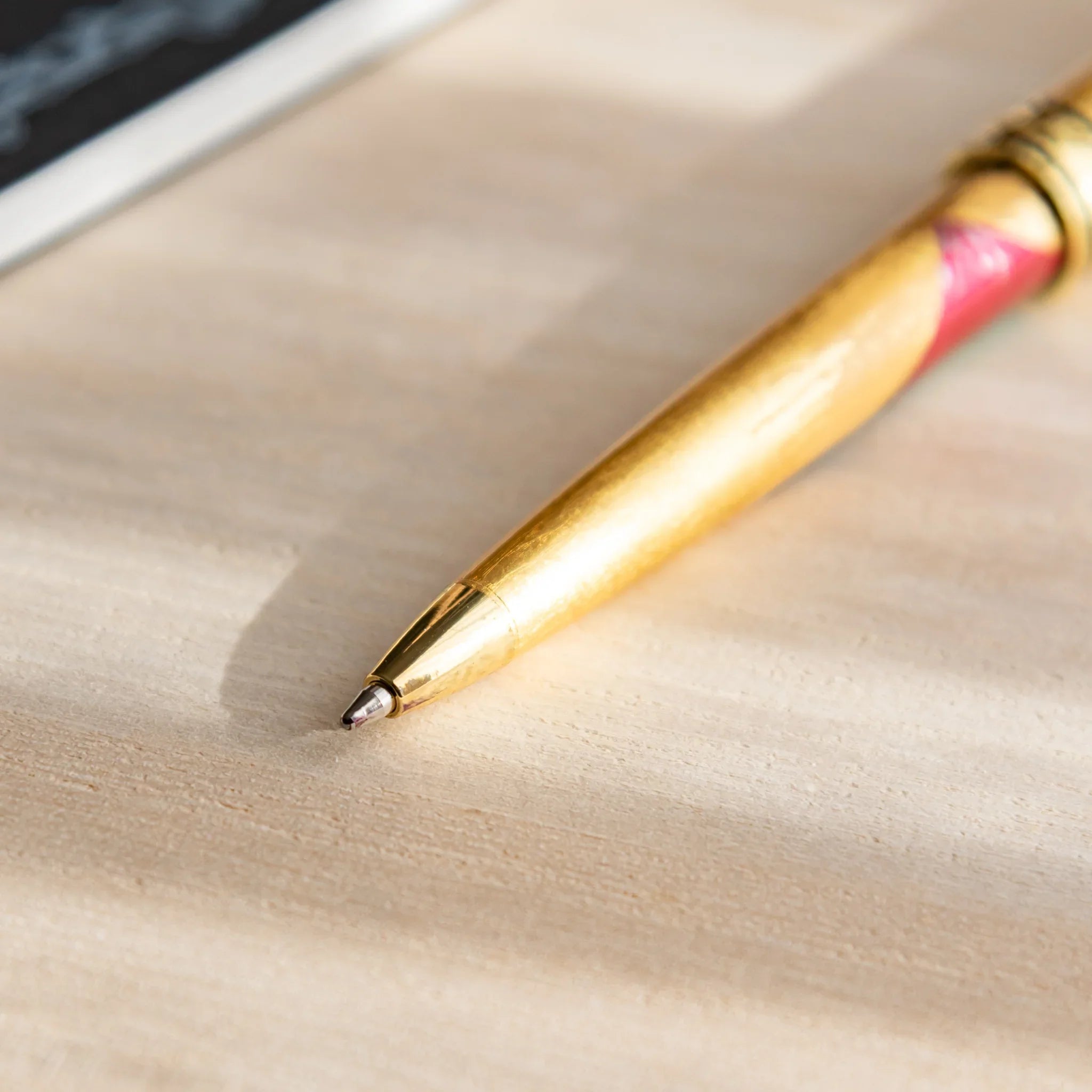 Gold Leaf Mt. Fuji Japanese Ballpoint Pen tip resting on a desk, showing its gold body and red Fuji detail near the grip.