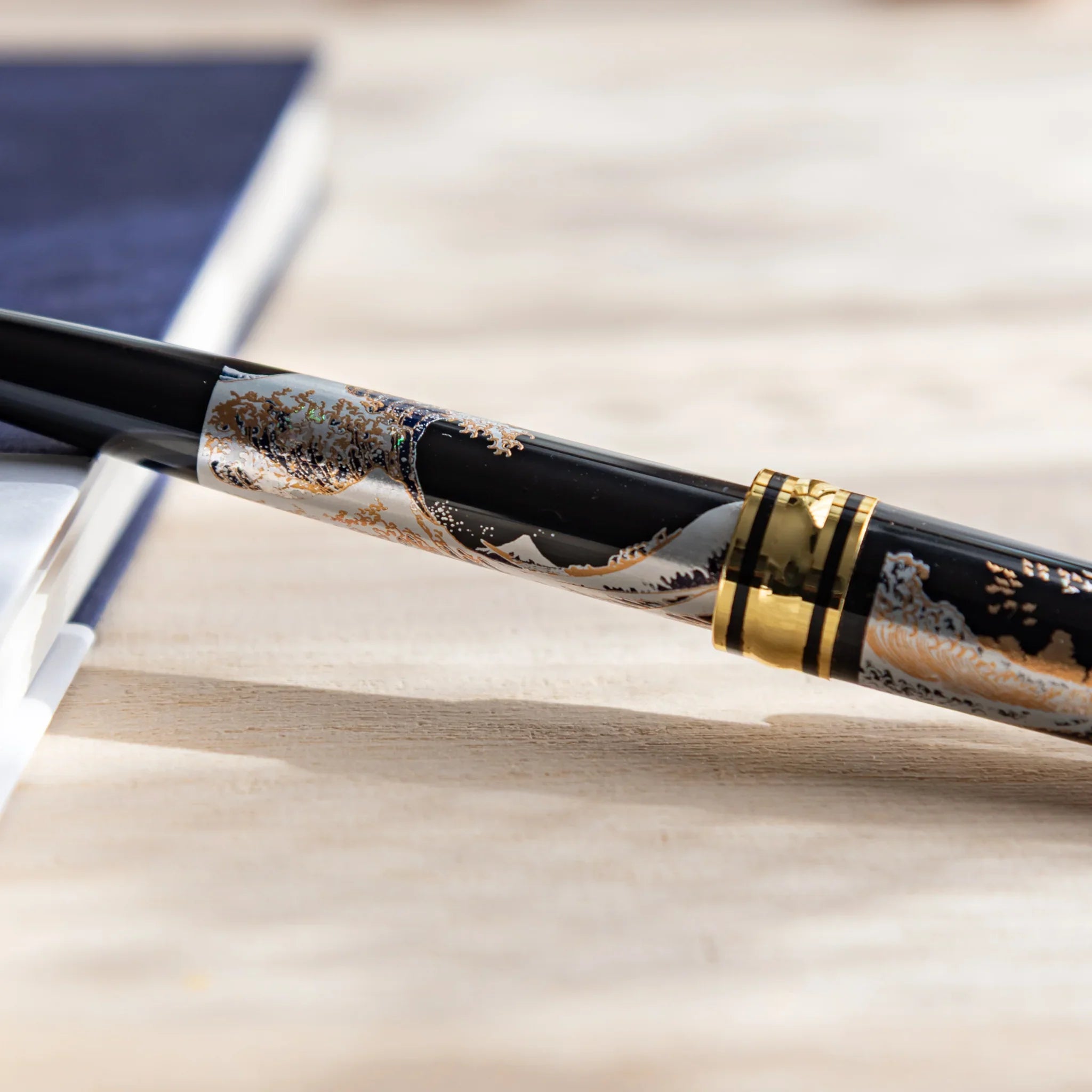 Japanese Ballpoint Pen with Great Wave design placed in the desk showing gold accents, black lacquer body.