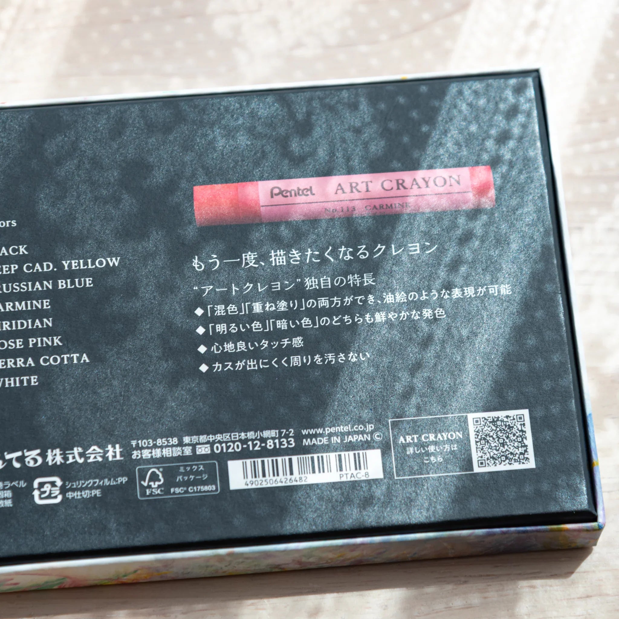 Pentel Art Crayon 8-color box tilted showing black back panel with color list and colorful front artwork visible at bottom