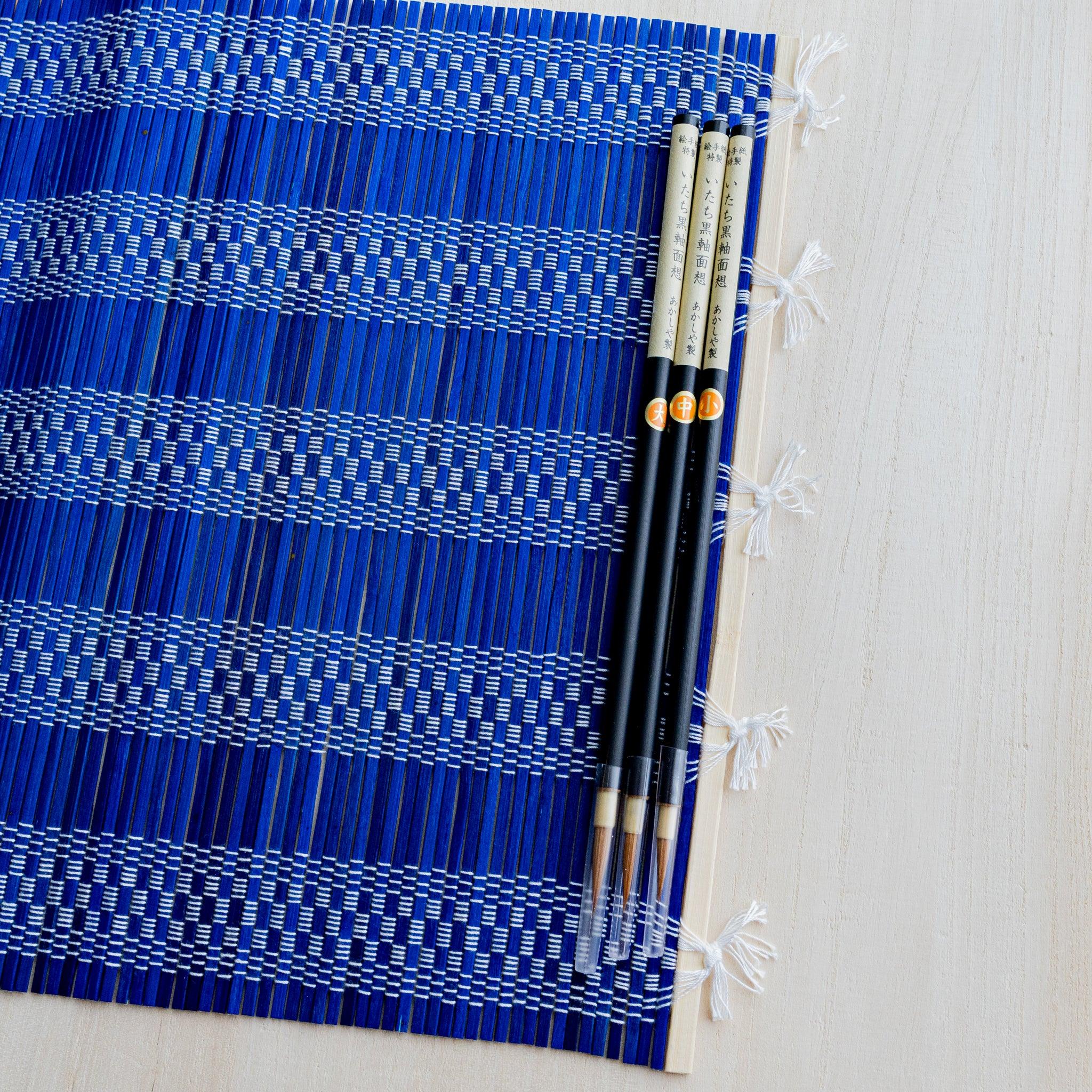 Akashiya bamboo brush roll, blue, unrolled showing the woven mat surface
