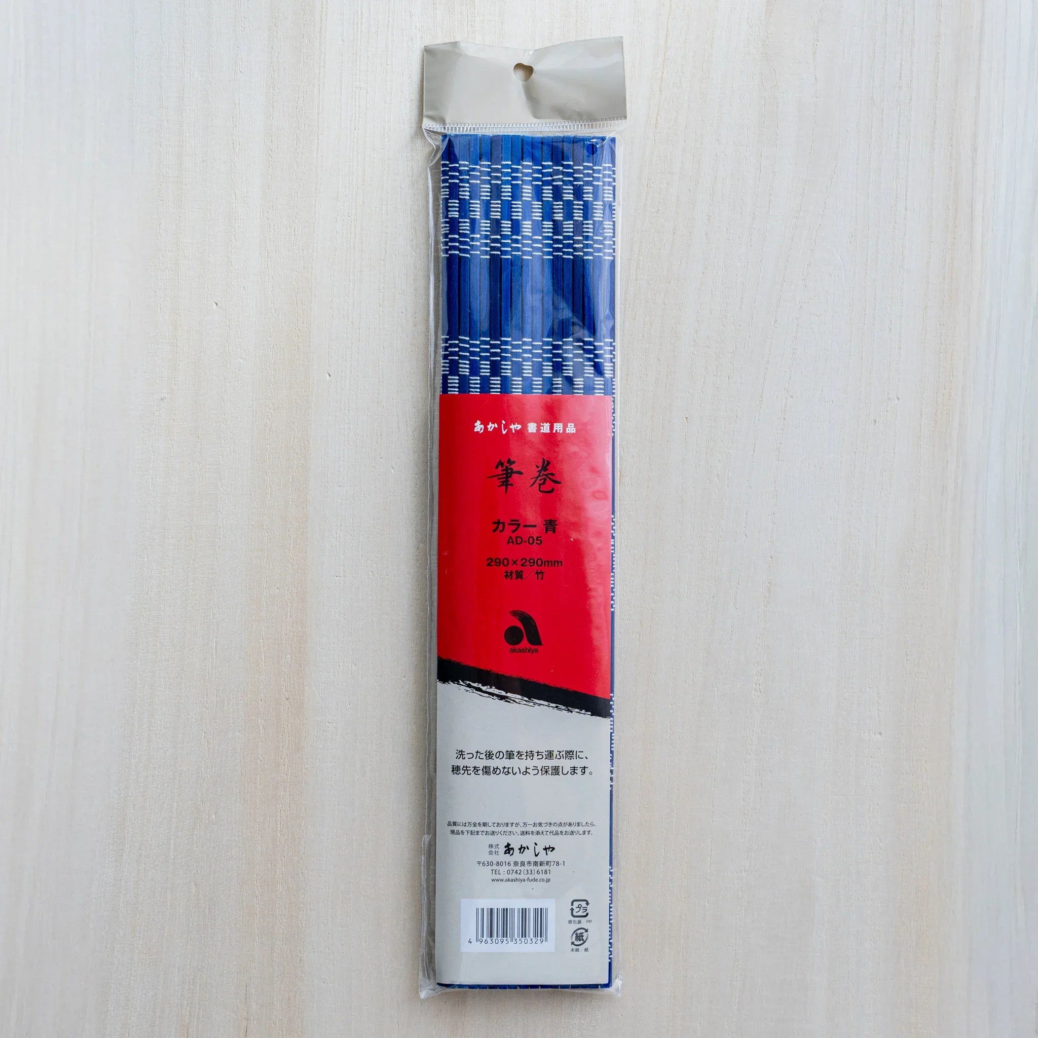 Akashiya bamboo brush holder roll, blue, on a light wood background