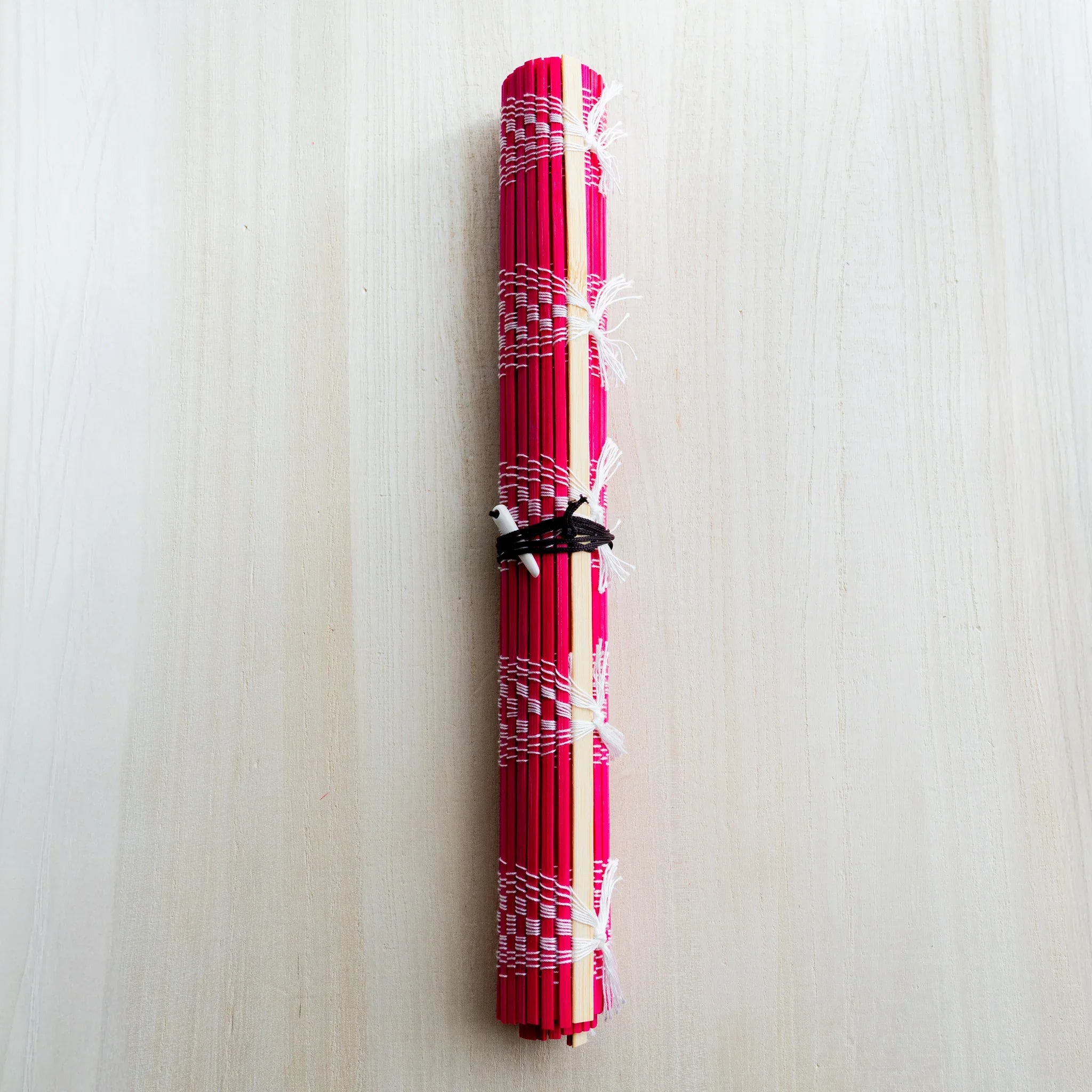 Akashiya bamboo brush roll, red variant with white checkered weave, rolled and tied