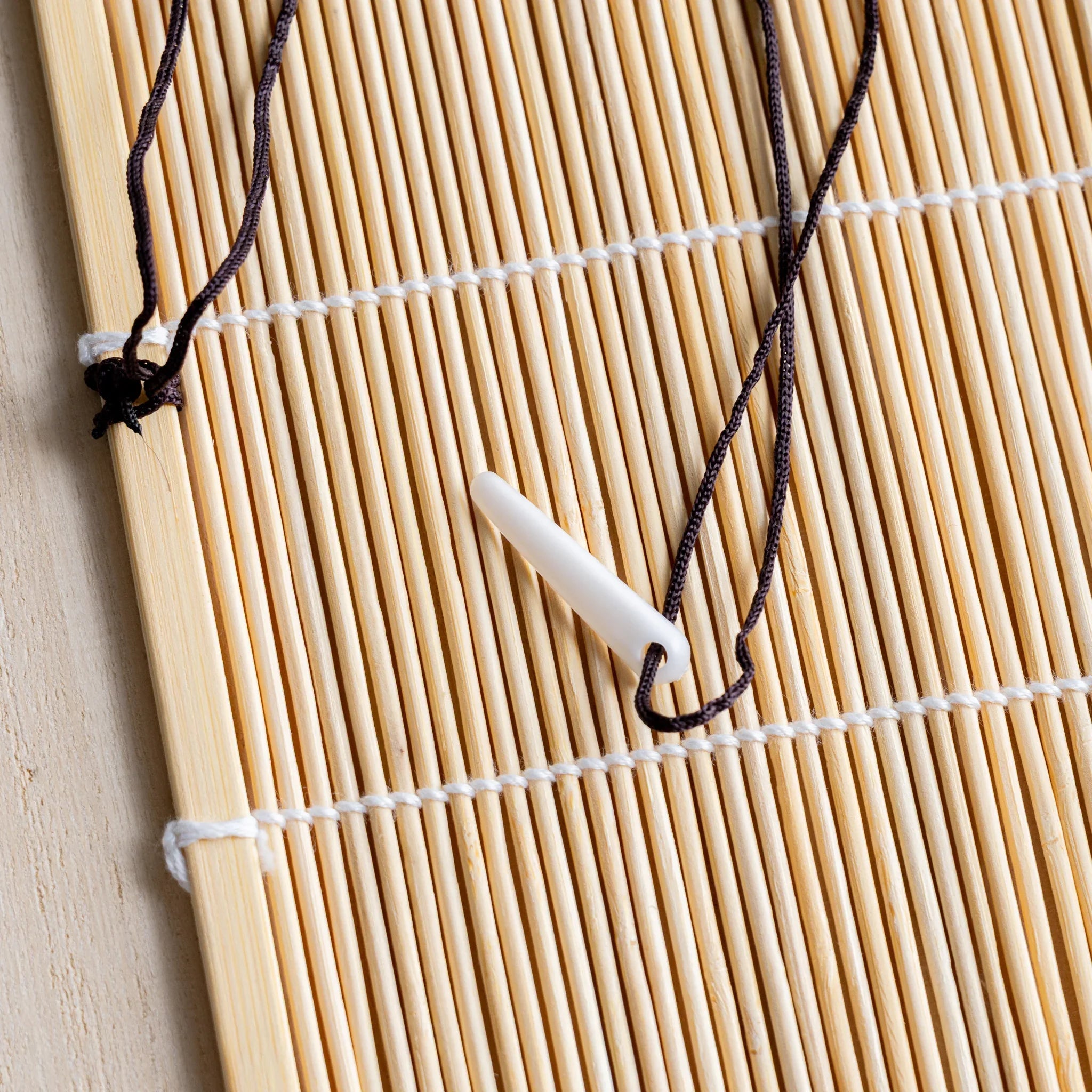 Akashiya fudemaki bamboo brush wrap unrolled, with cotton tie cord across the mat