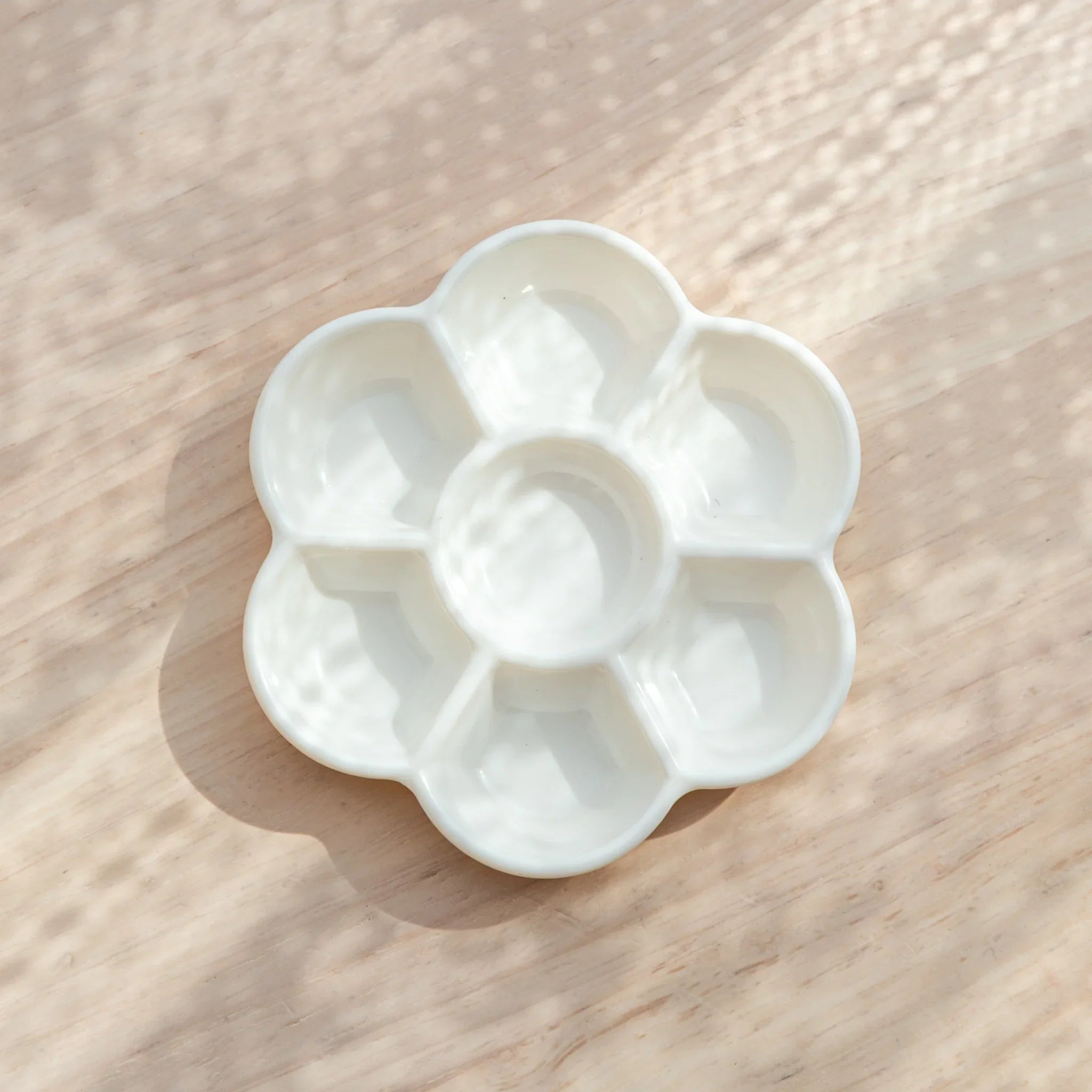 White ceramic flower-shaped paint palette with eight individual round wells and one center circular well