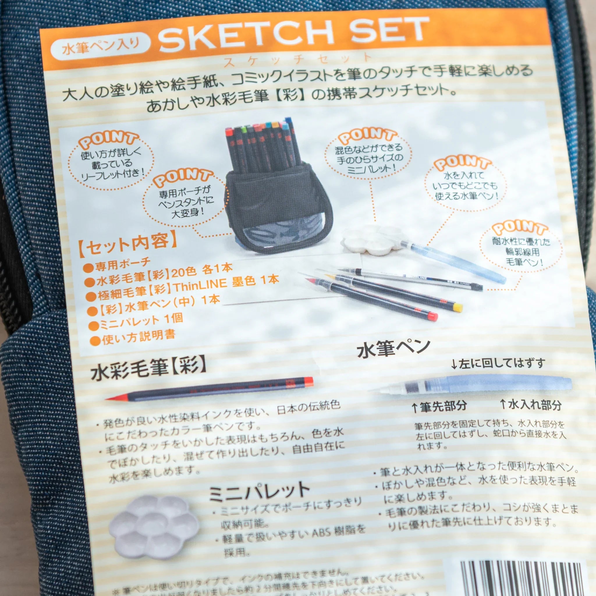 Watercolor brush pens standing upright and organized in foam holder insert inside protective blue denim carrying case