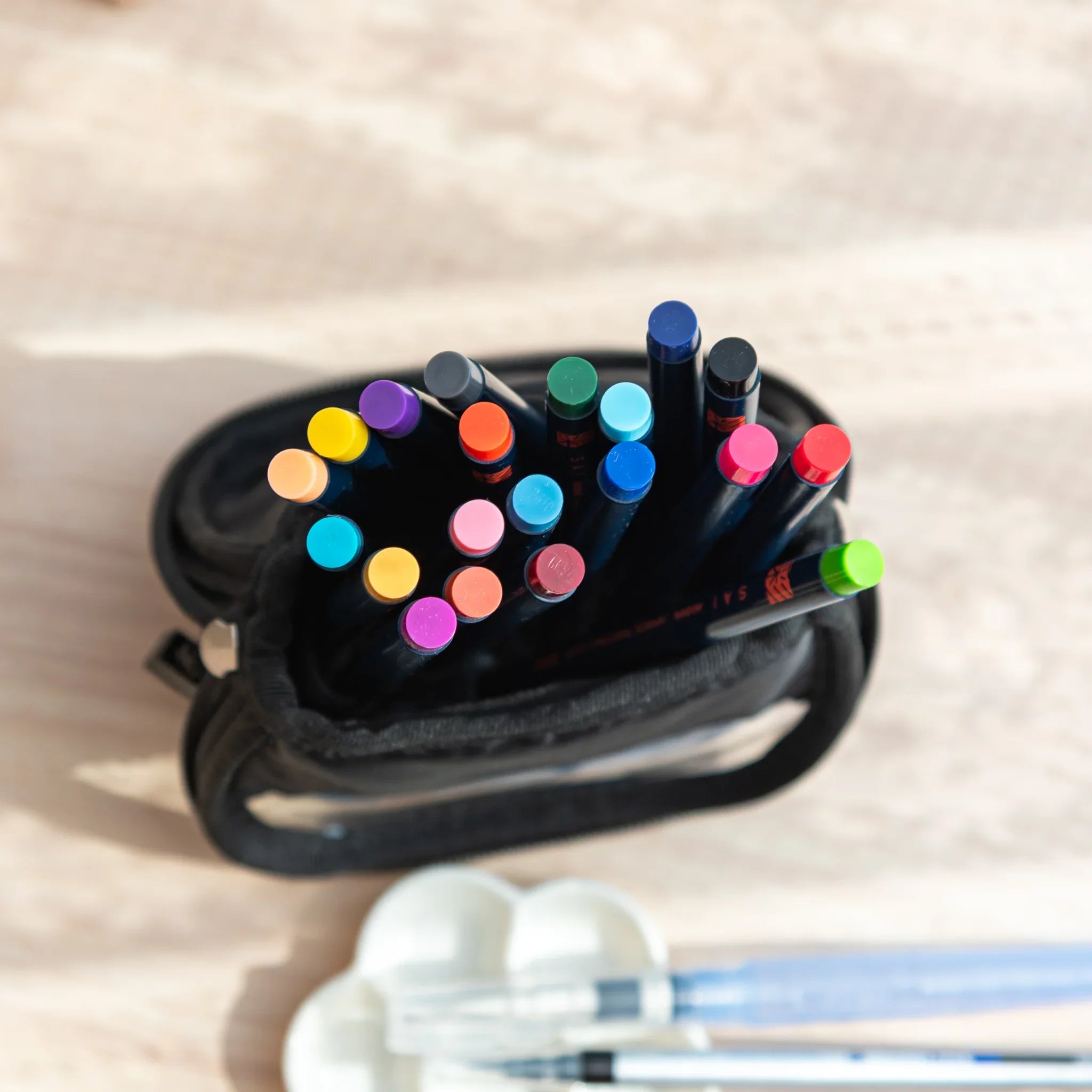 Unzipped denim case revealing assorted Japanese watercolor brush pens organized inside with foam insert