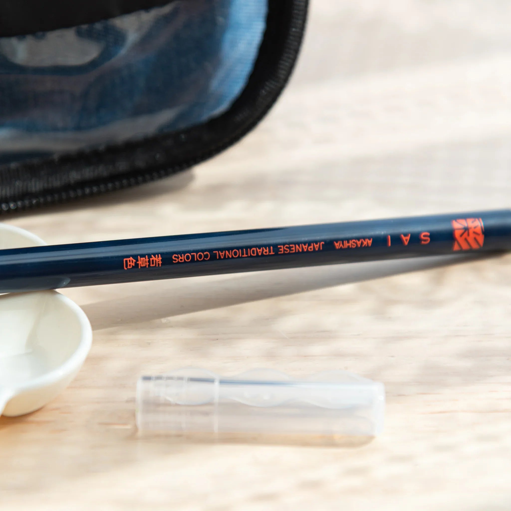 Akashiya Japanese Traditional Colors brush pen with orange logo, placed near palette and cap for arts and crafts use.