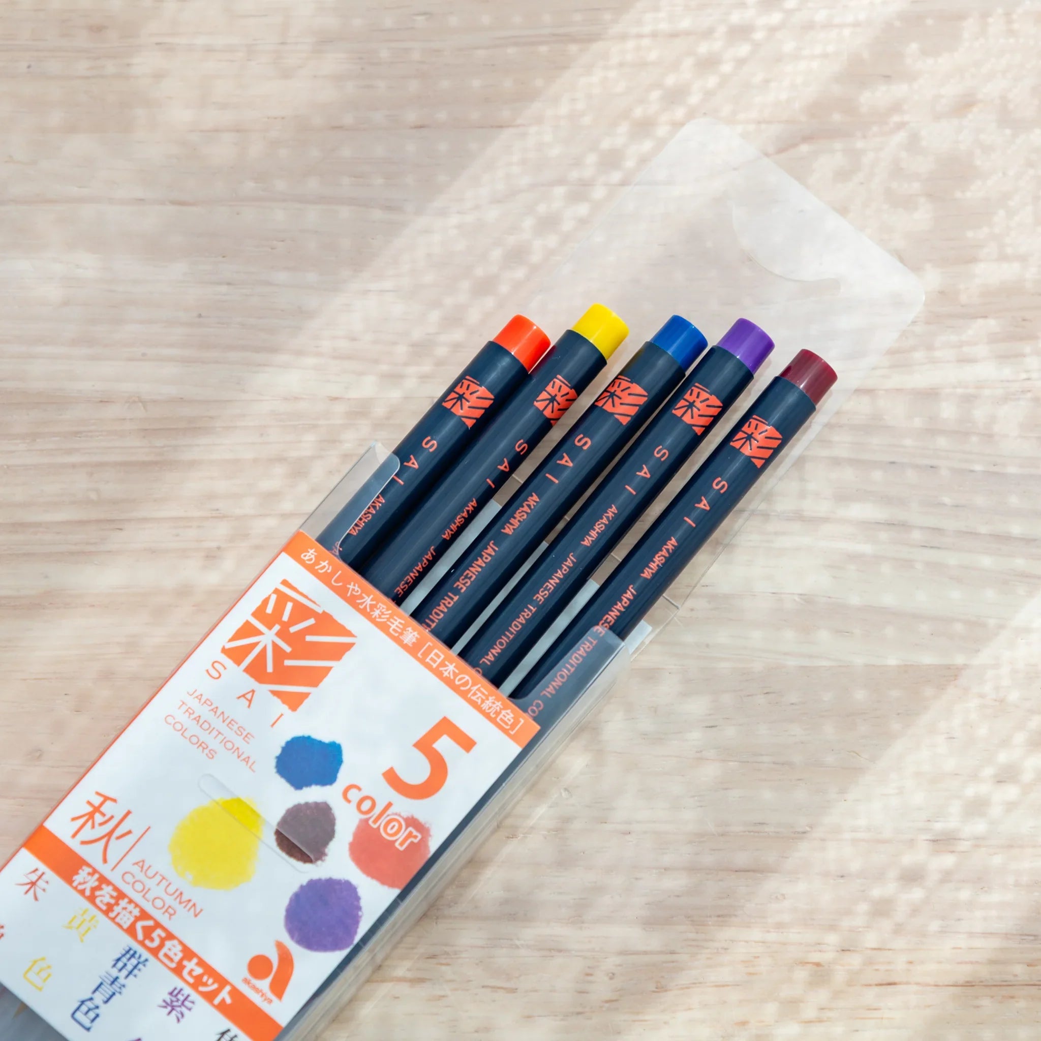 Five warm-toned watercolor brush pens displaying autumn colors including burnt orange, rust, gold, brown