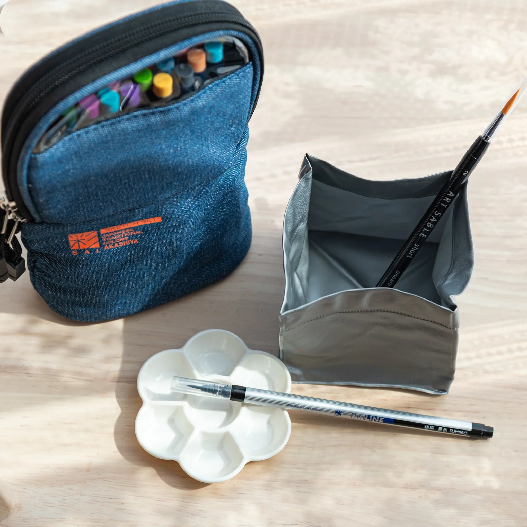 Complete watercolor art kit showing brush pens, water cup, and storage case for portable painting setup