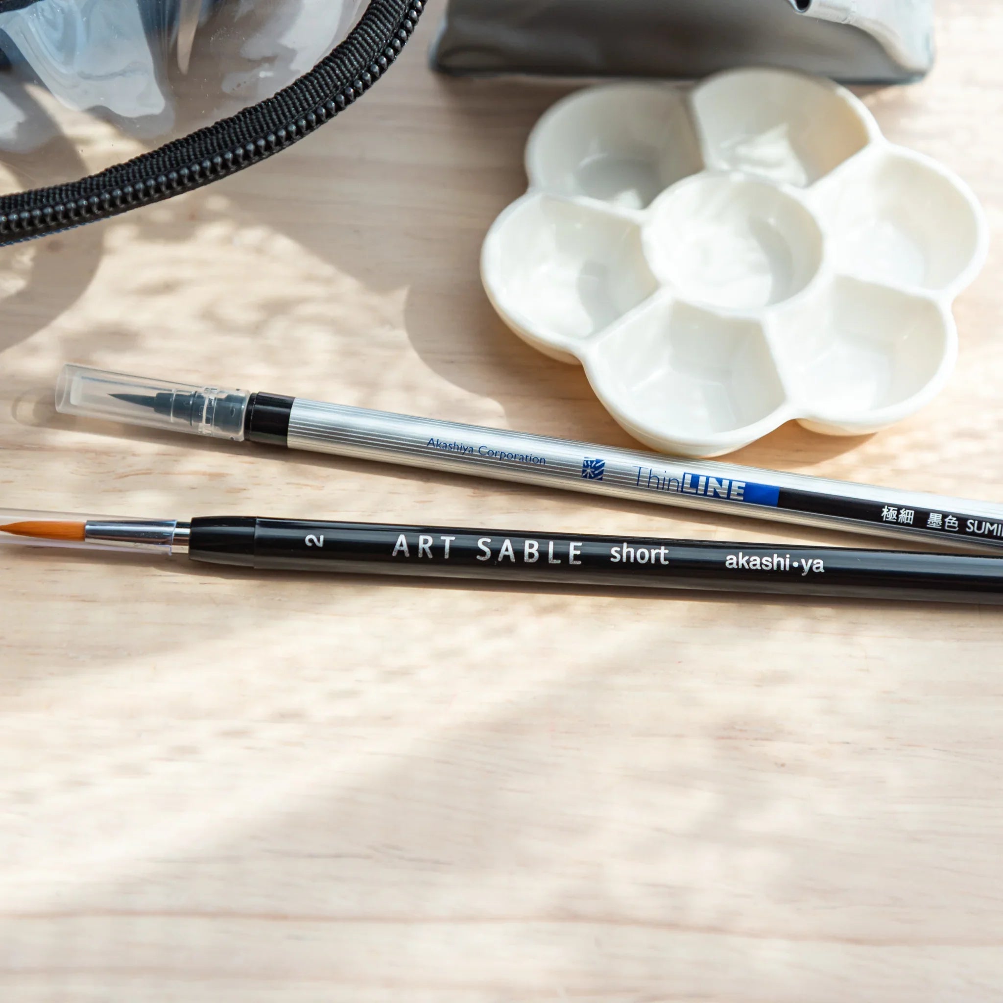 Folding water cup positioned with brush pens showing practical setup for outdoor watercolor art painting