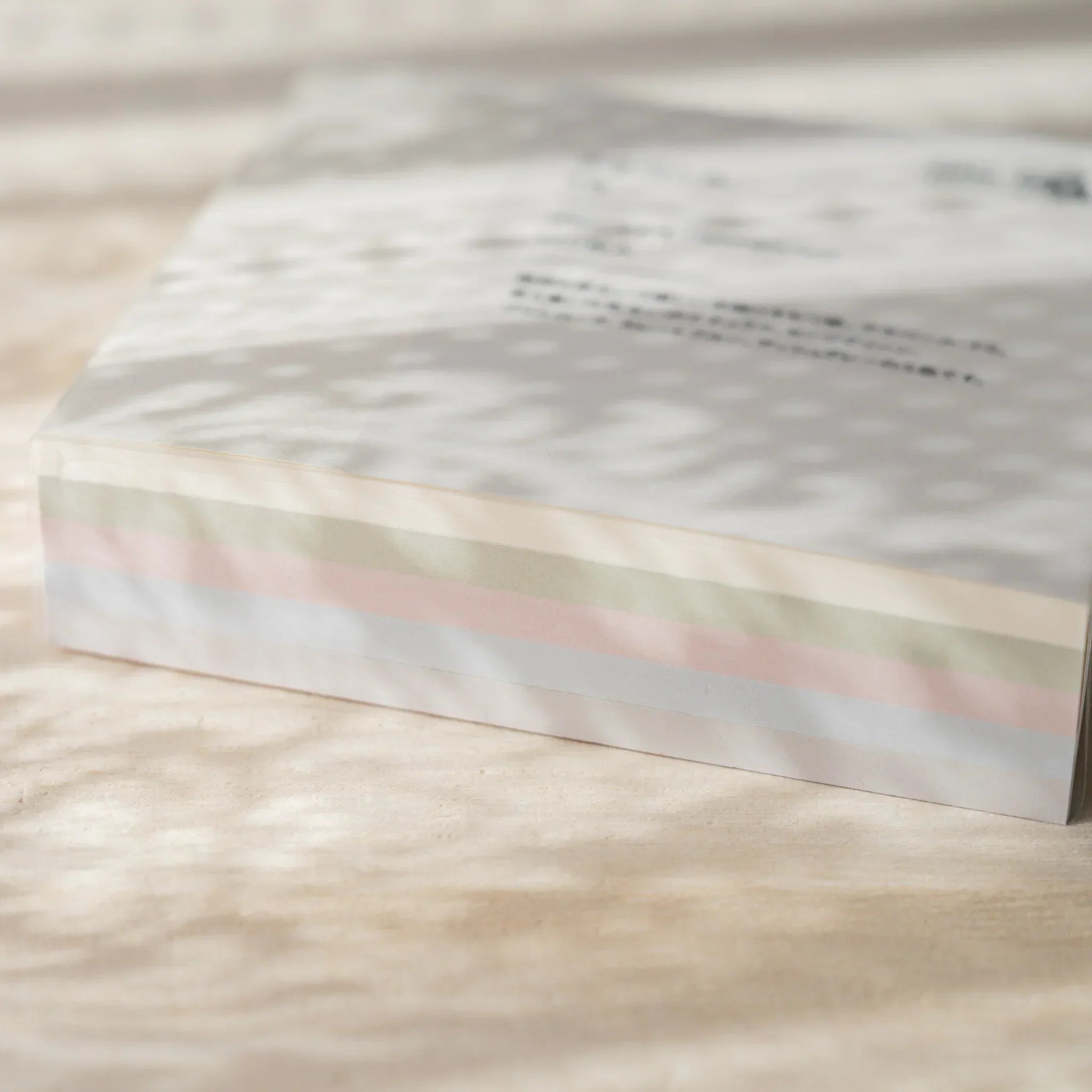 Five pastel colored memo pad blocks stacked together showing pink, blue, yellow, green, and cream paper colors