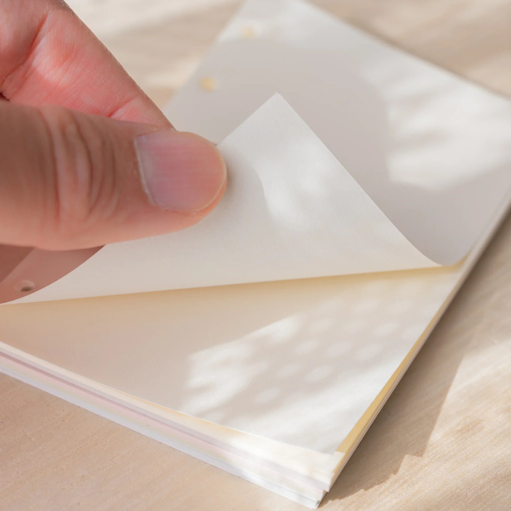 Hand peeling a translucent cream Araveal Mini 6 planner refill sheet from the pack.