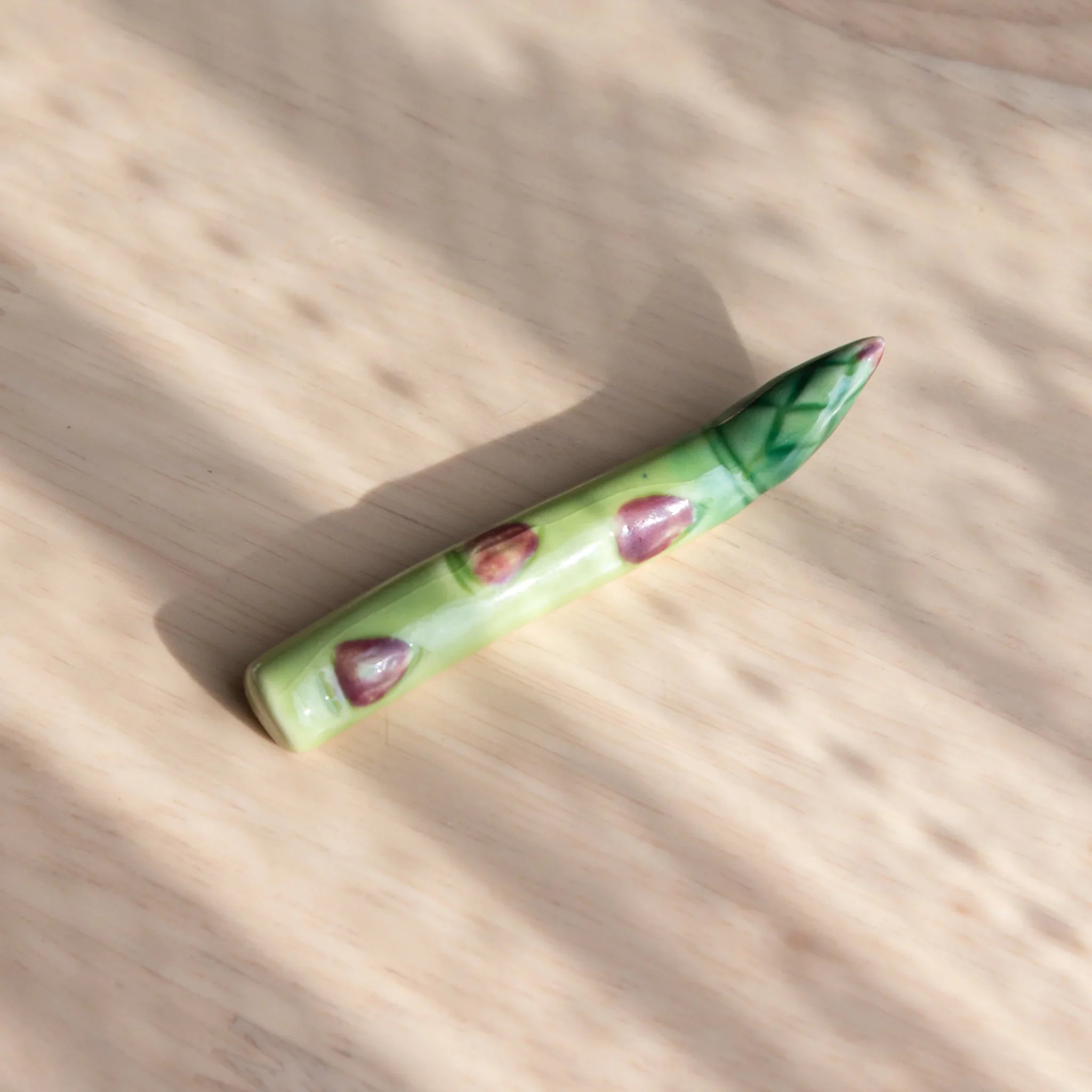 Green asparagus-shaped Japanese handcrafted ceramic pen rest with bundled spears and central groove pen close shot
