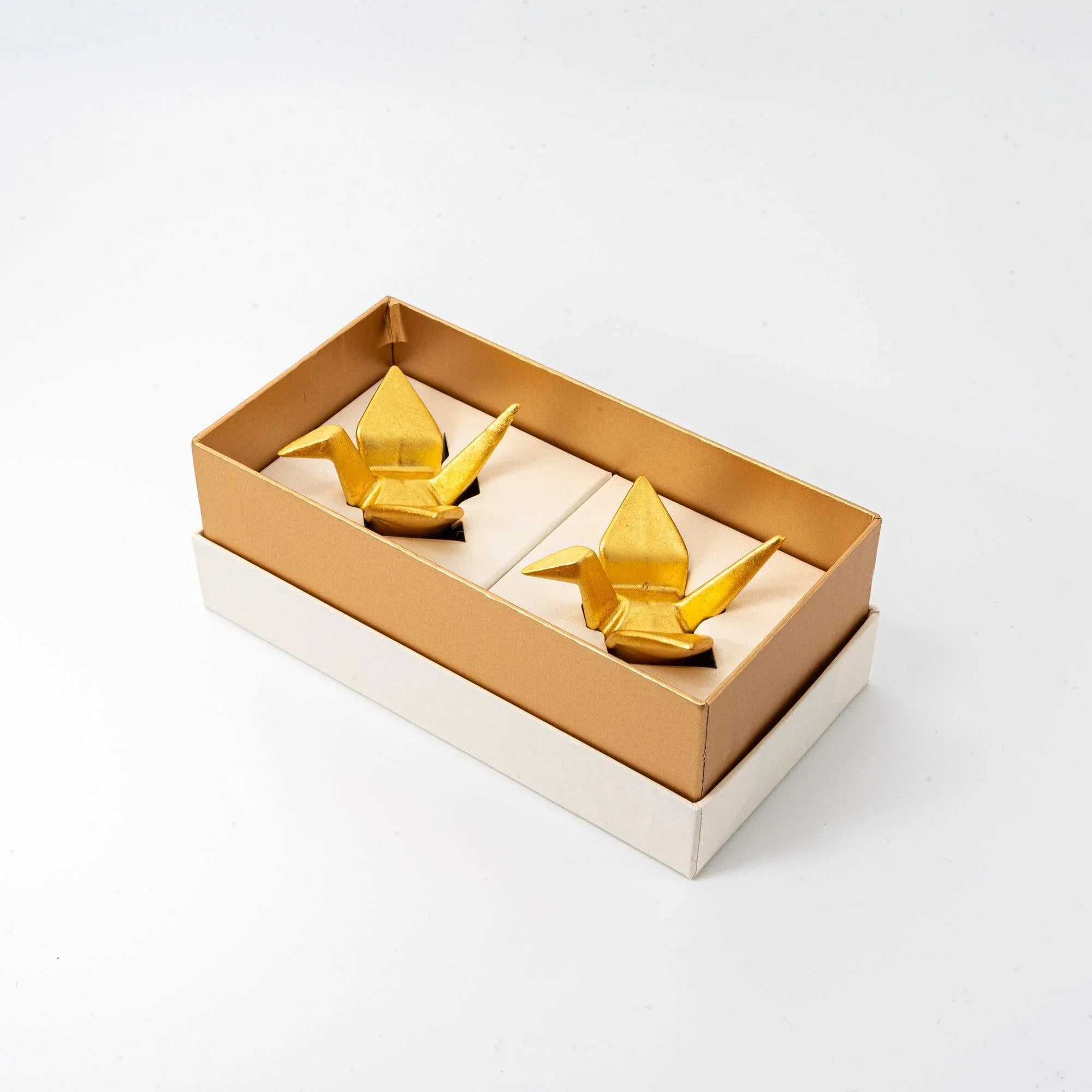 Two golden Japanese auspicious crane pen rests arranged on white background for editorial product styling display