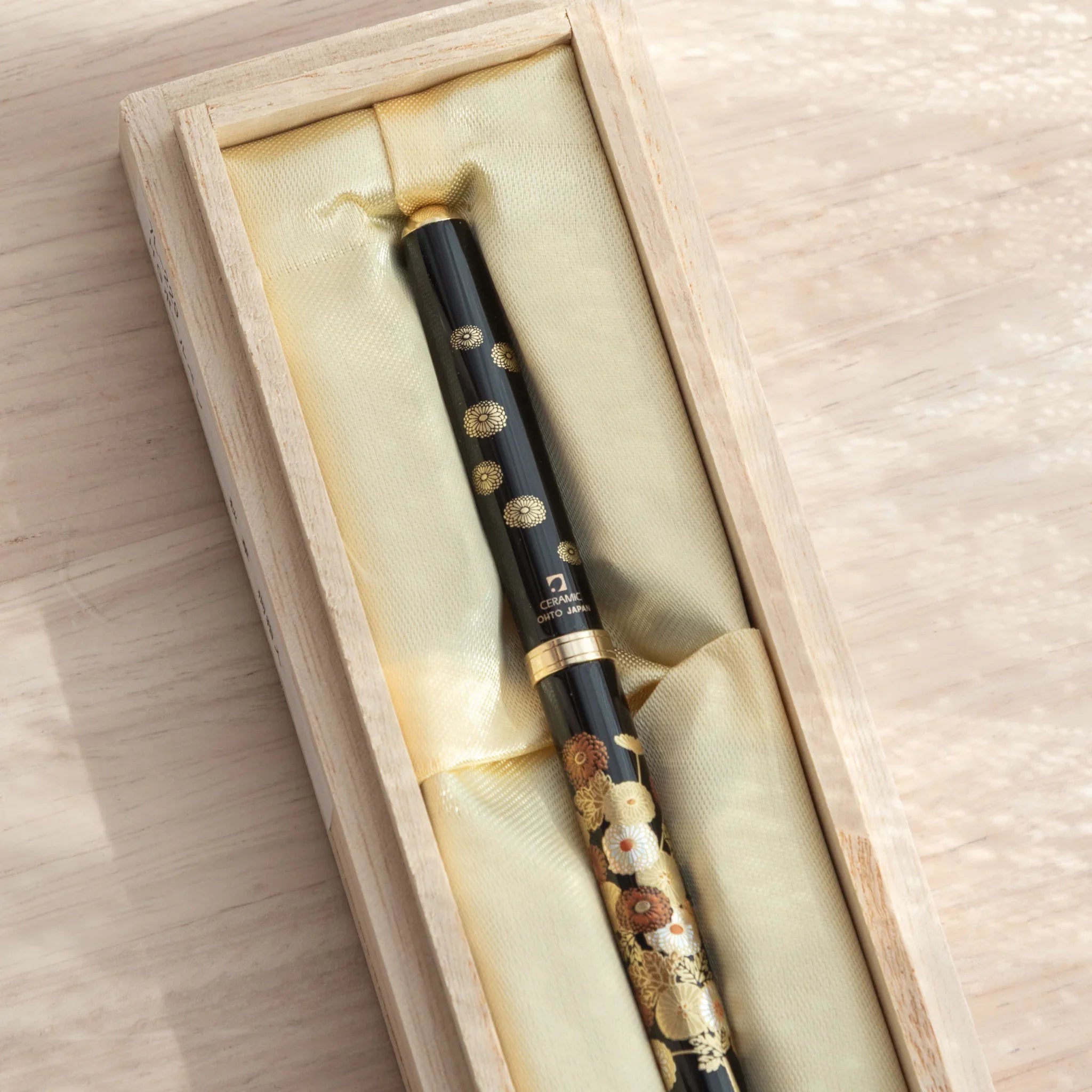 Close-up of a Japanese Ballpoint Pen with intricate gold and red floral patterns on a black background.