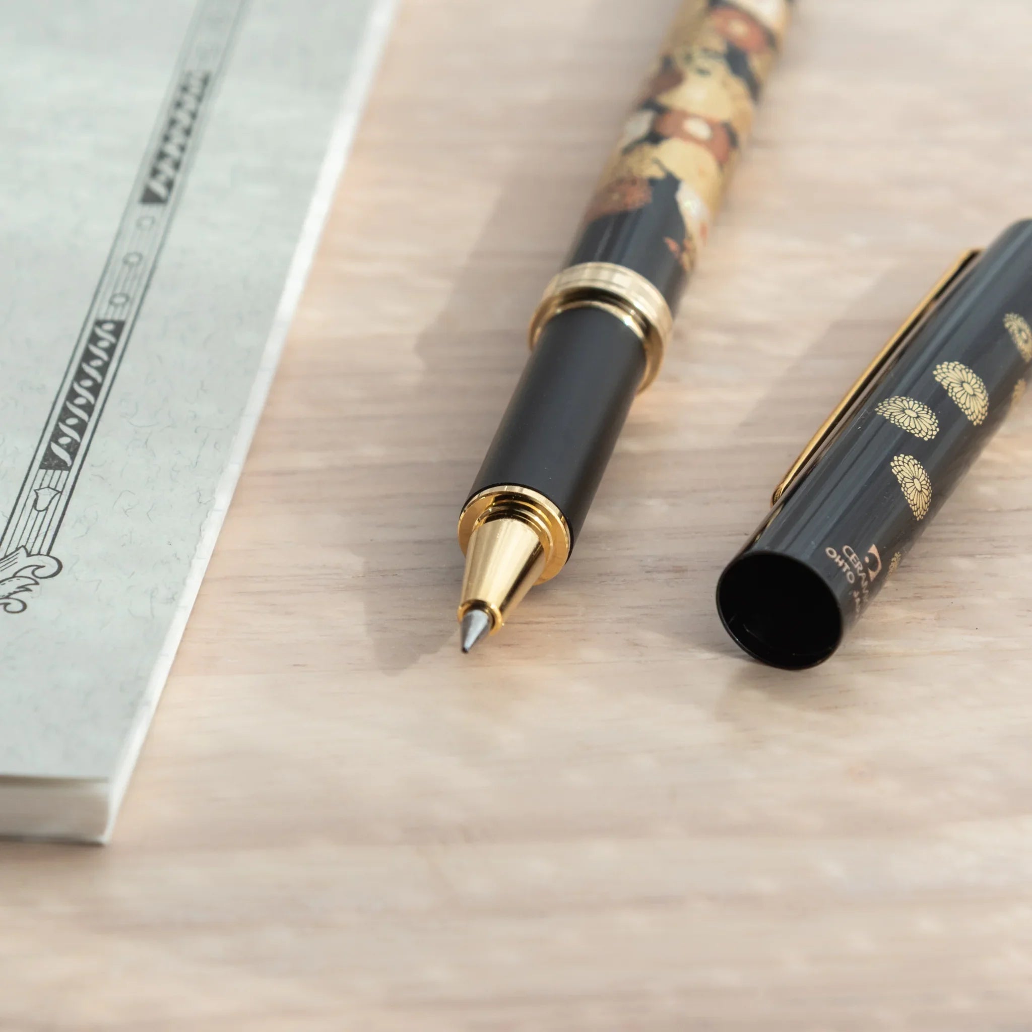 Capped-off Japanese Ballpoint Pen with Lacquer finish, featuring golden chrysanthemum design on a black glossy body.
