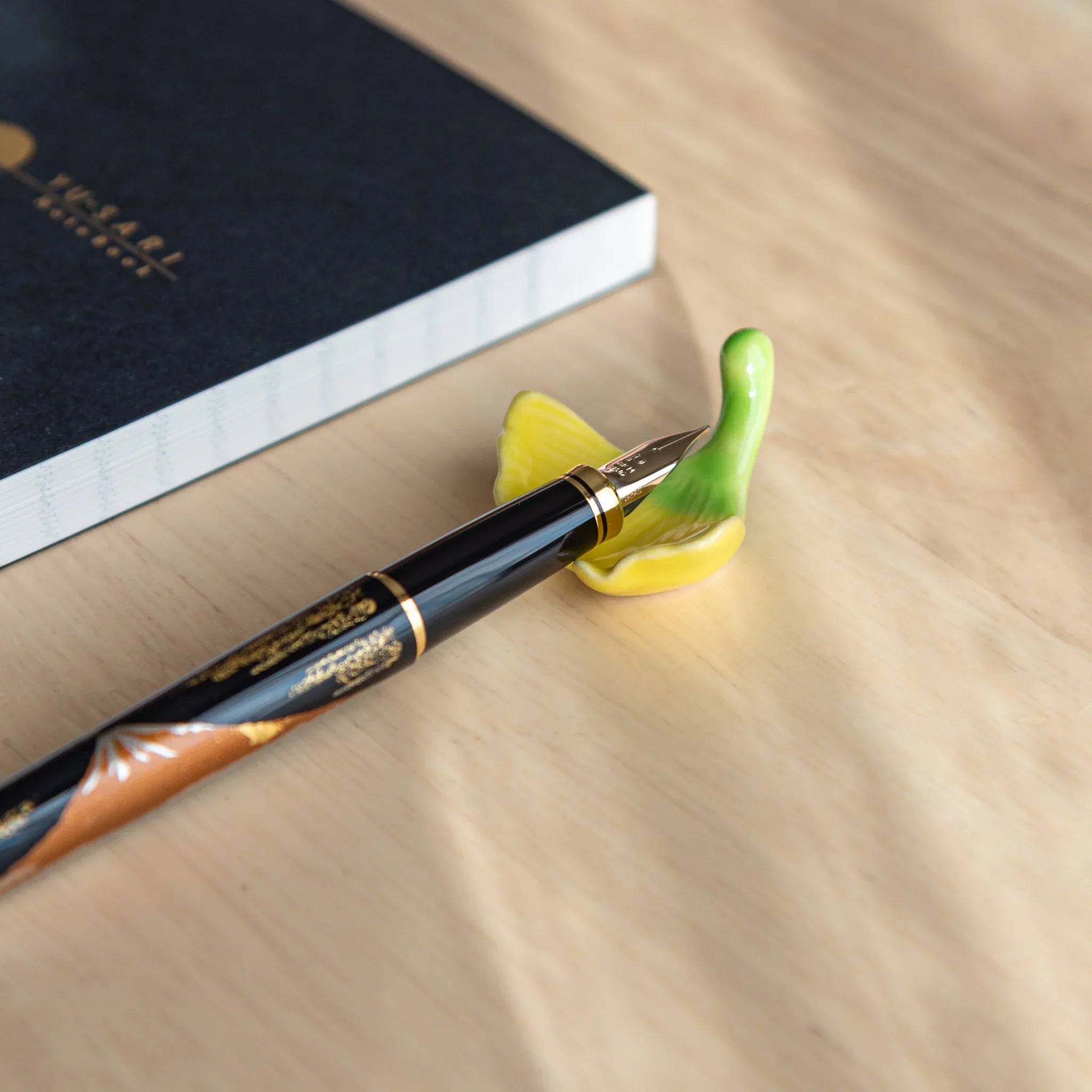 Warm-toned autumn leaf pen rest in brown and red shades with detailed carved leaf vein pattern showing seasonal artistry