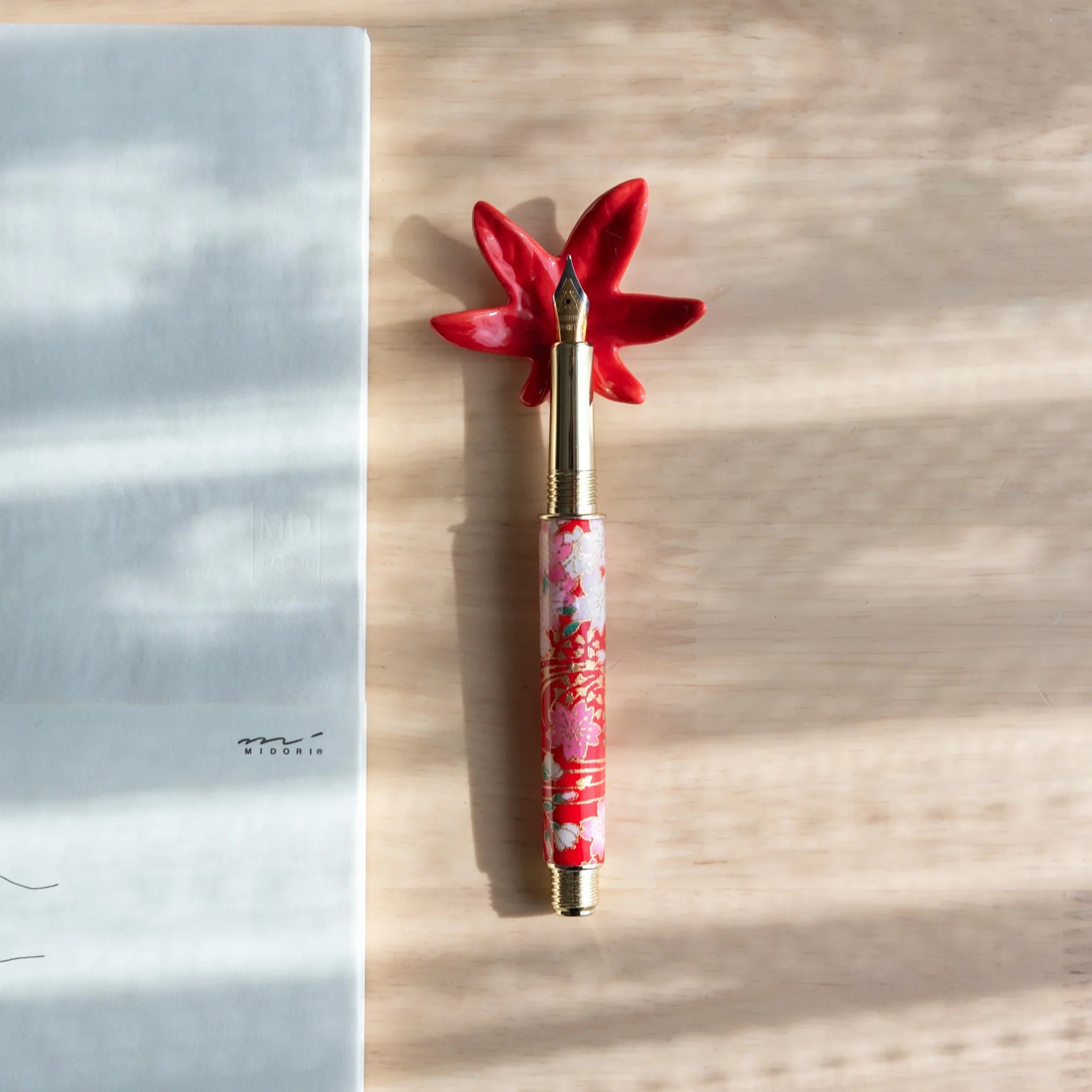 Red and brown autumn leaf shaped handcrafted pen rest with traditional fall color tone palette and veined detail carving