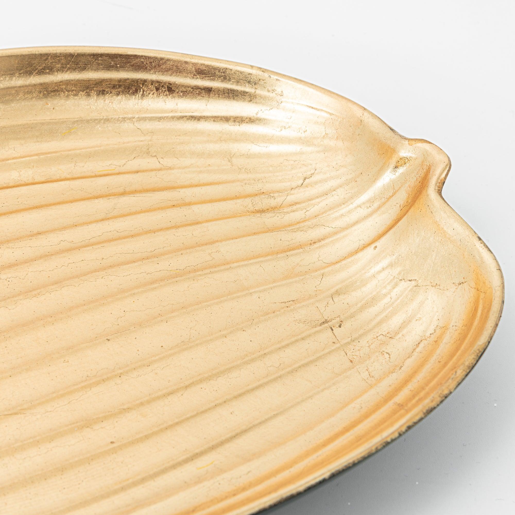 A close-up of the textured gold surface of a leaf-shaped tray, highlighting its intricate details.
