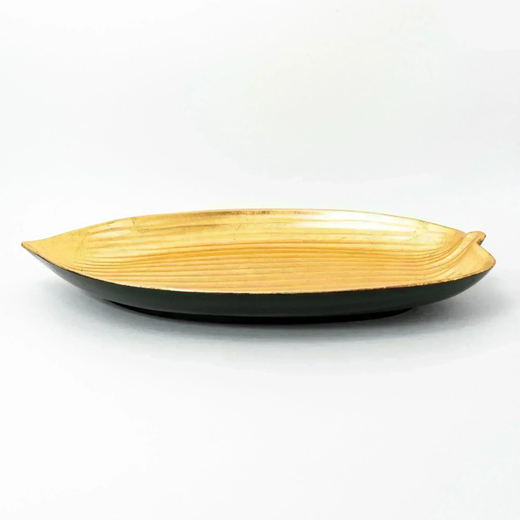 A side view of the gold tray, showcasing its sleek, curved leaf-inspired design.