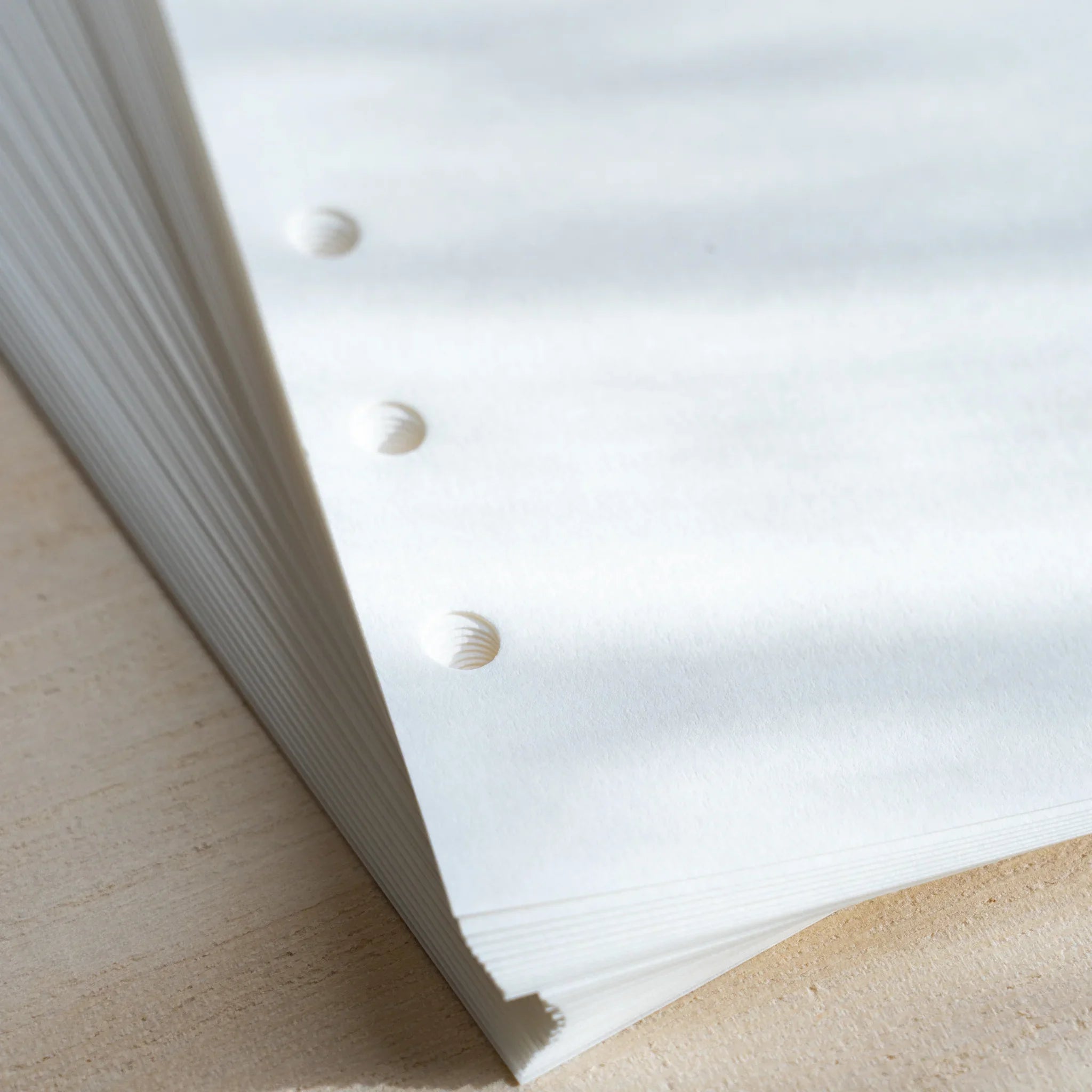 Close-up of Japanese Stationery Bank Paper refill showing stacked white sheets with crisp six-hole punches and smooth, clean edges.