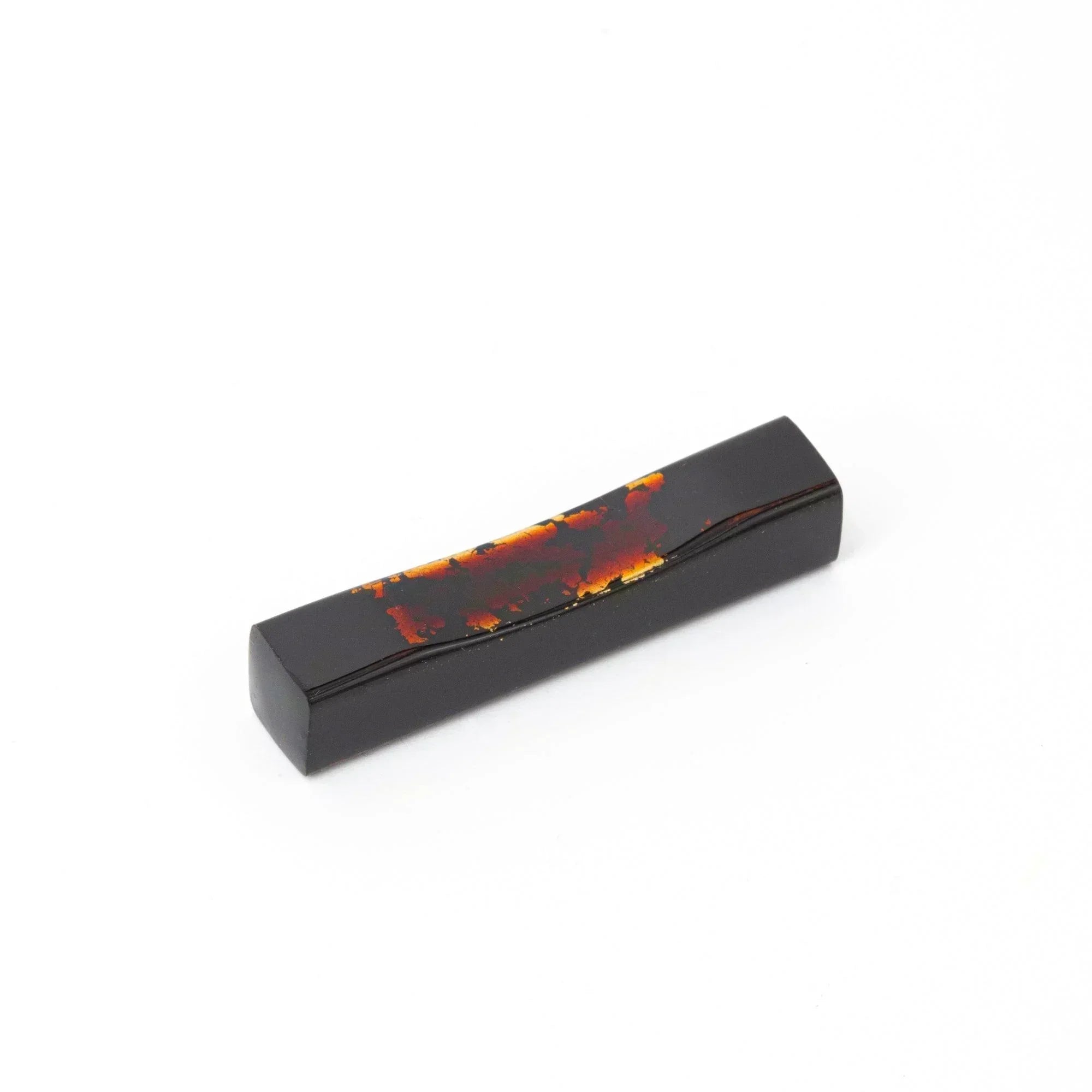 A single black and red marbled Japanese stationery pen rest with a curved design against a white background.
