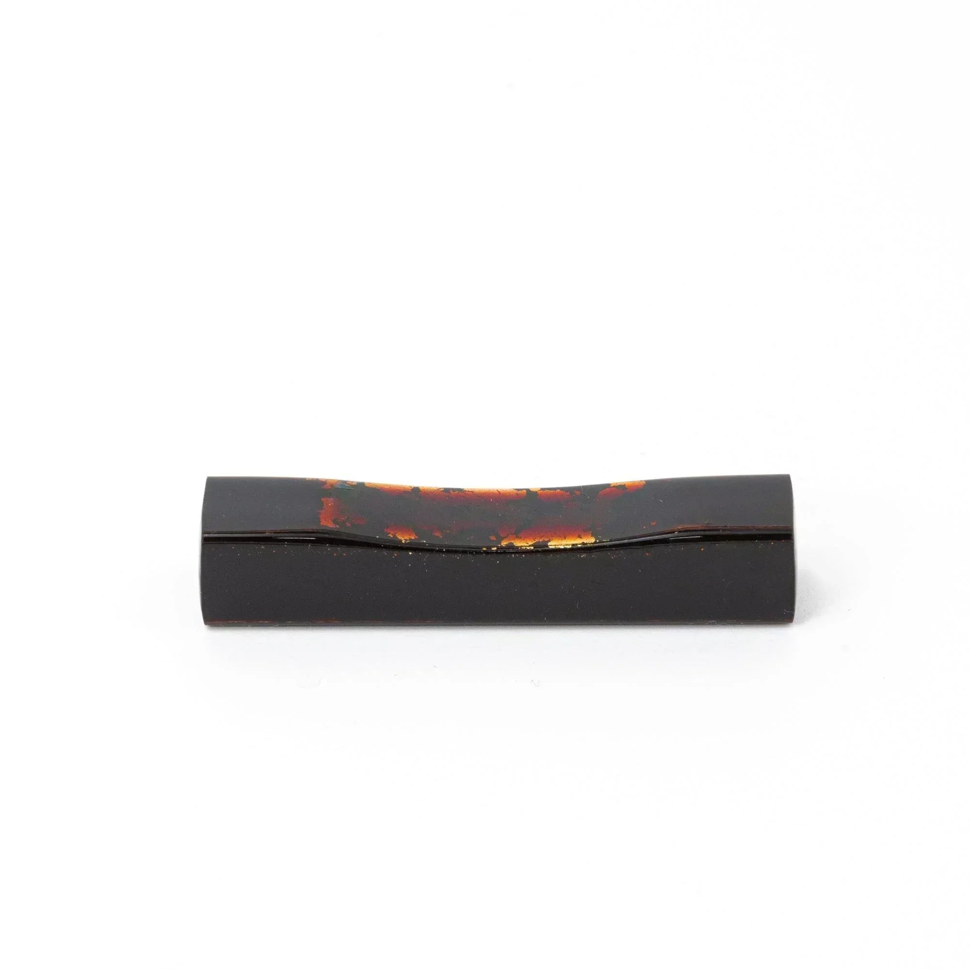 A single black and red marbled Japanese stationery pen rest with a curved design against a white background.