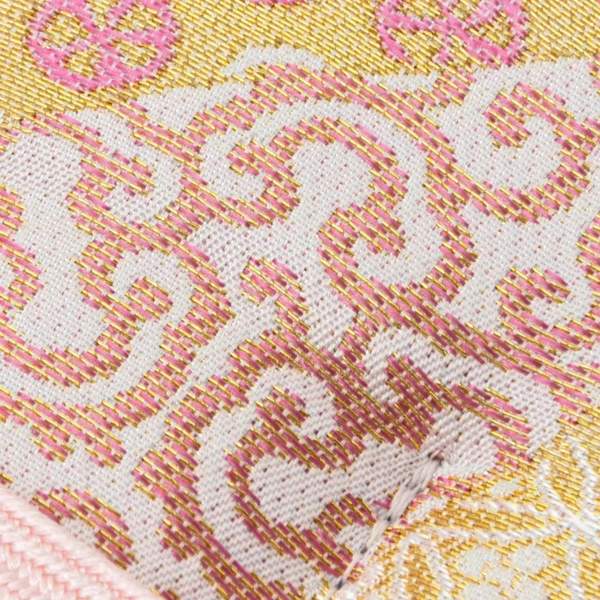 A detailed view of a Japanese fountain pen case, showcasing gold-threaded swirls and pink motifs in its elegant Nishijin silk design.