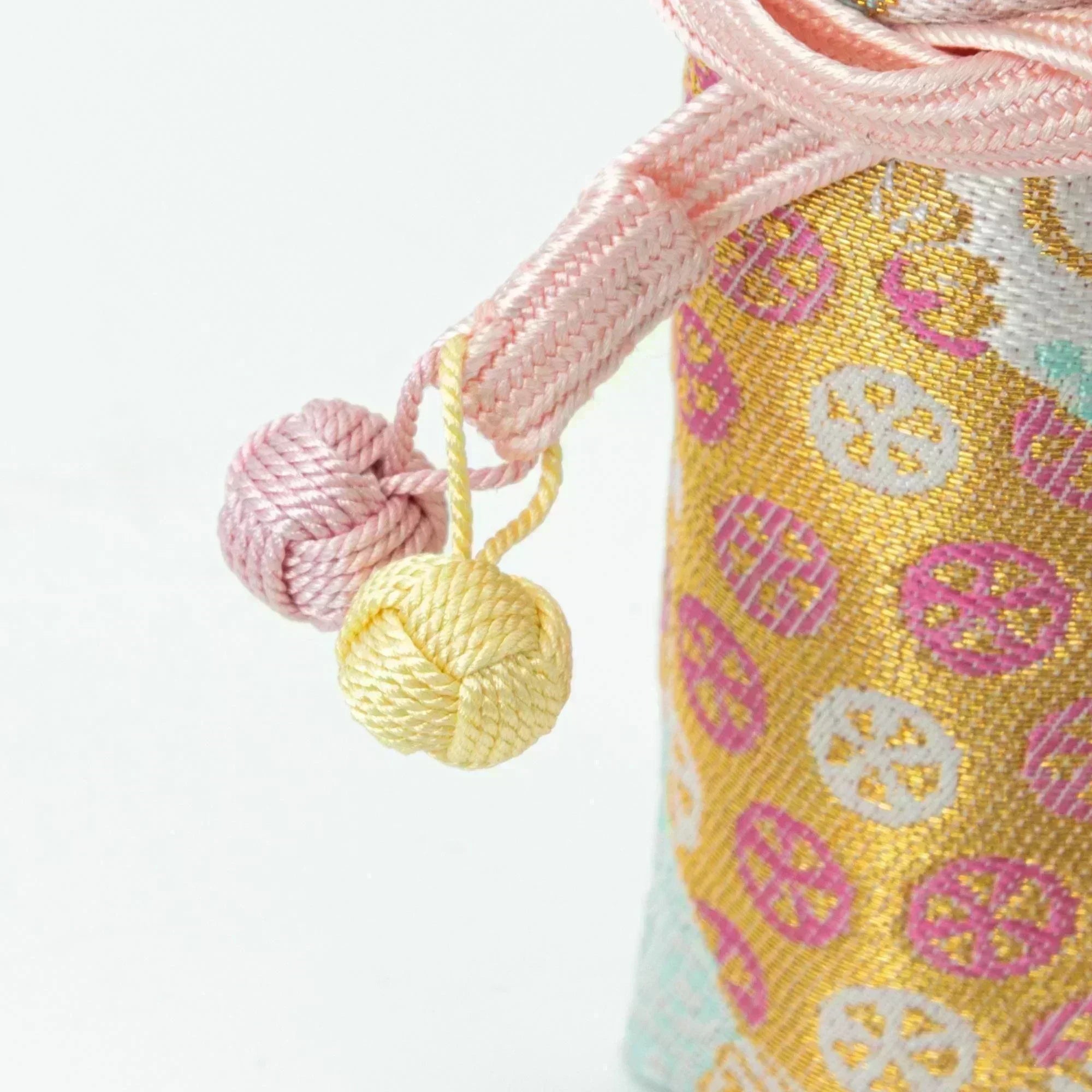 A close-up of the pink cord with yellow and pink decorative knots from a Japanese fountain pen case made of Nishijin silk.