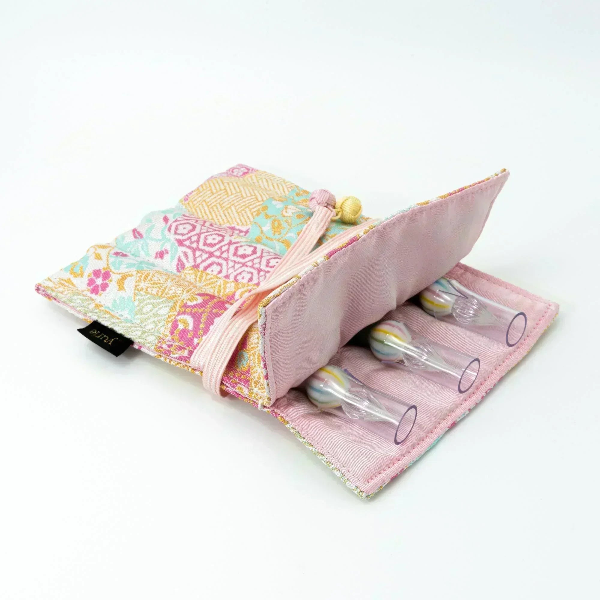 A pastel-colored Japanese fountain pen case of Nishijin silk, open to display three decorative glass dip pens, with a pink fabric interior.