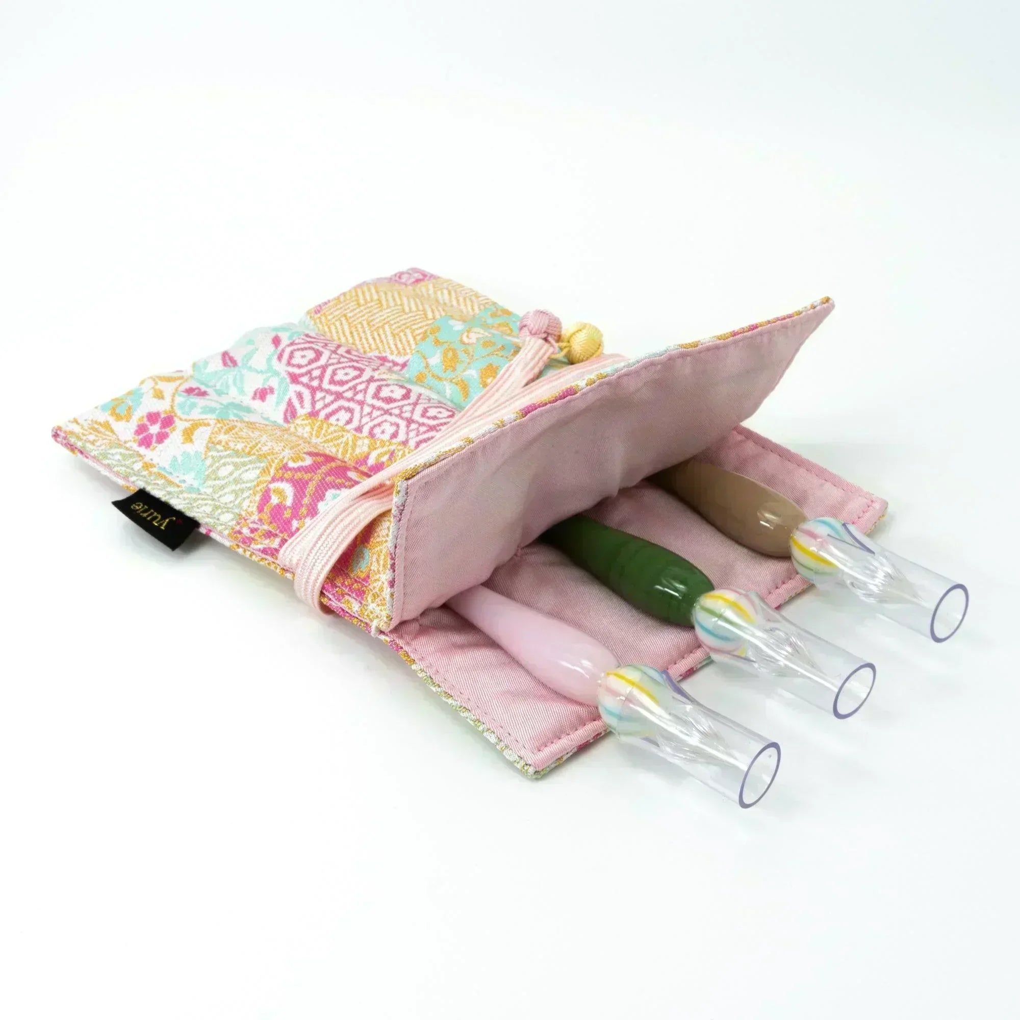 A pastel-colored Japanese fountain pen case of Nishijin silk, open to display three glass dip pens with multicolored handles, laid on a white surface.