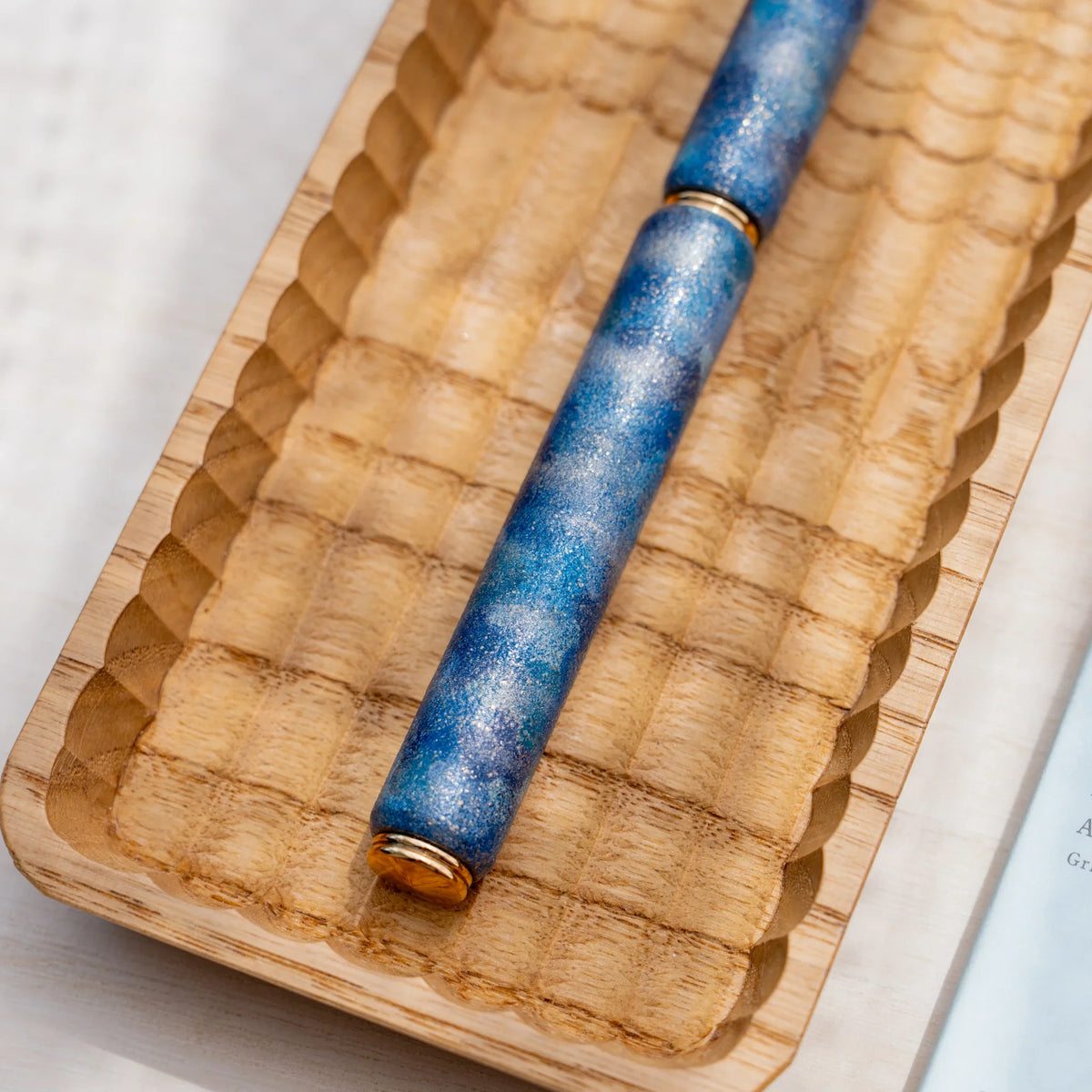 Close-up of the marbled color urushi surface on the blue zelkova wood rollerball pen