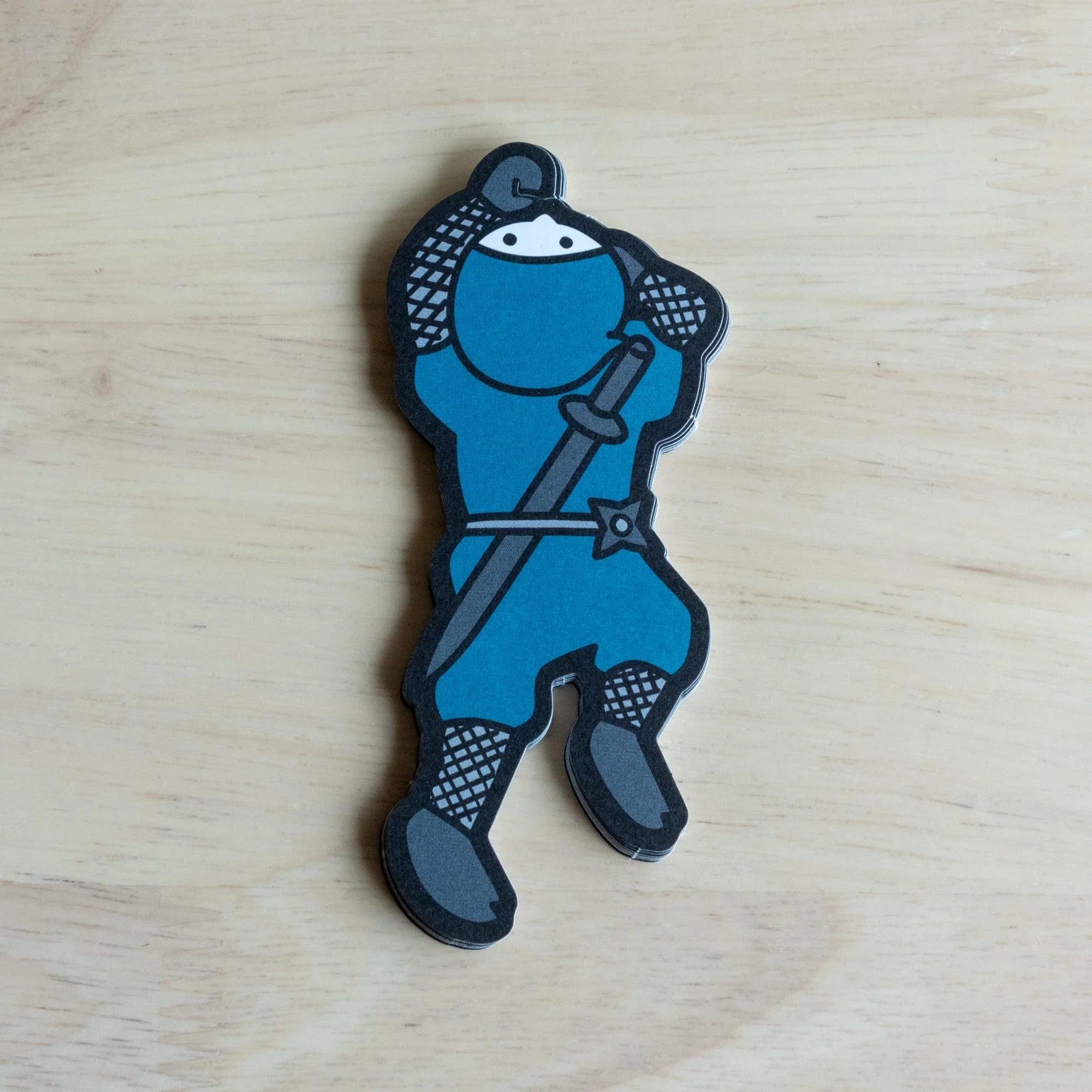 Close-up detail of blue ninja character showing white facial features, checkered pattern sleeves and dark boots