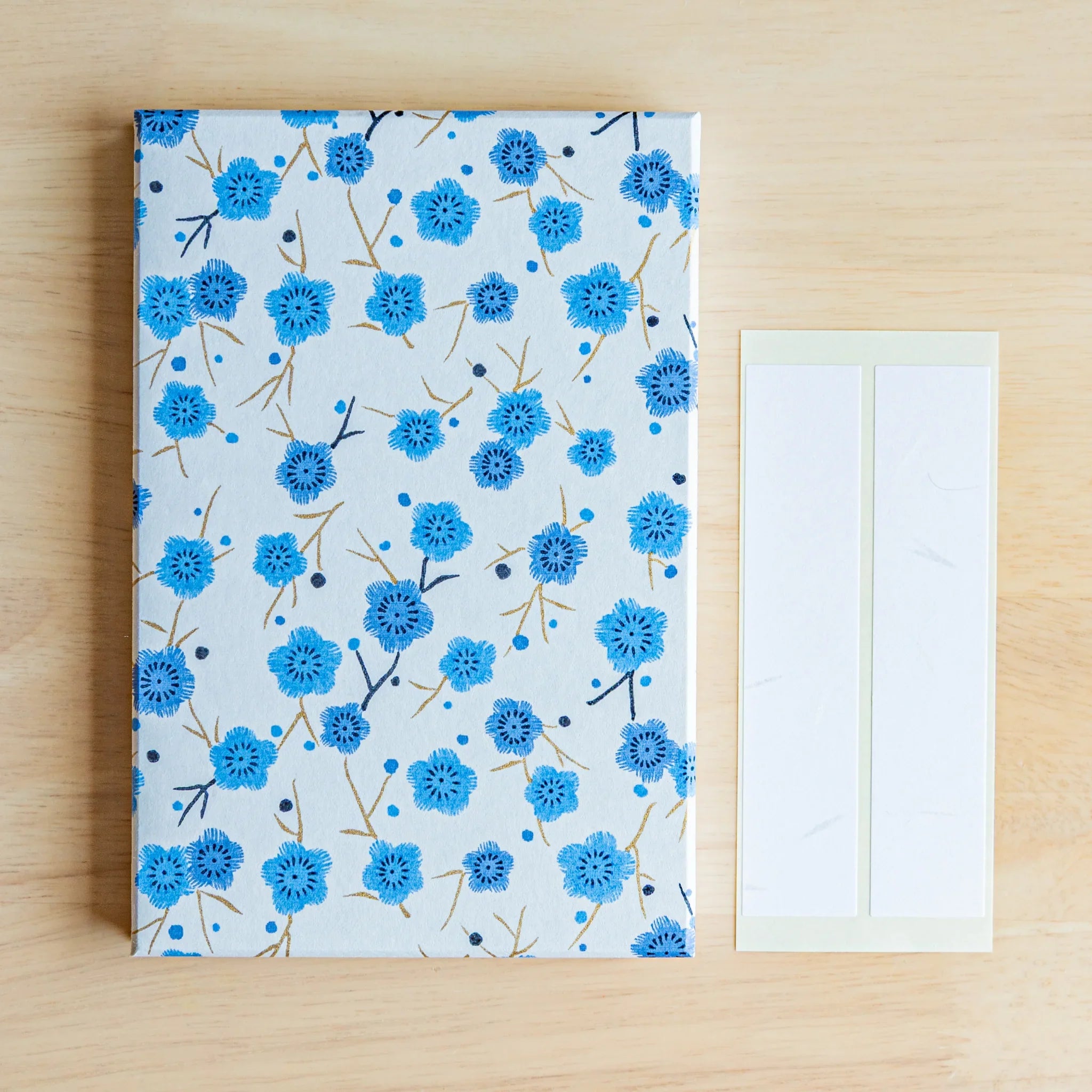 Flat lay overhead of closed Blue Plum Blossoms washi stamp book cover on wooden surface showing product quality and design