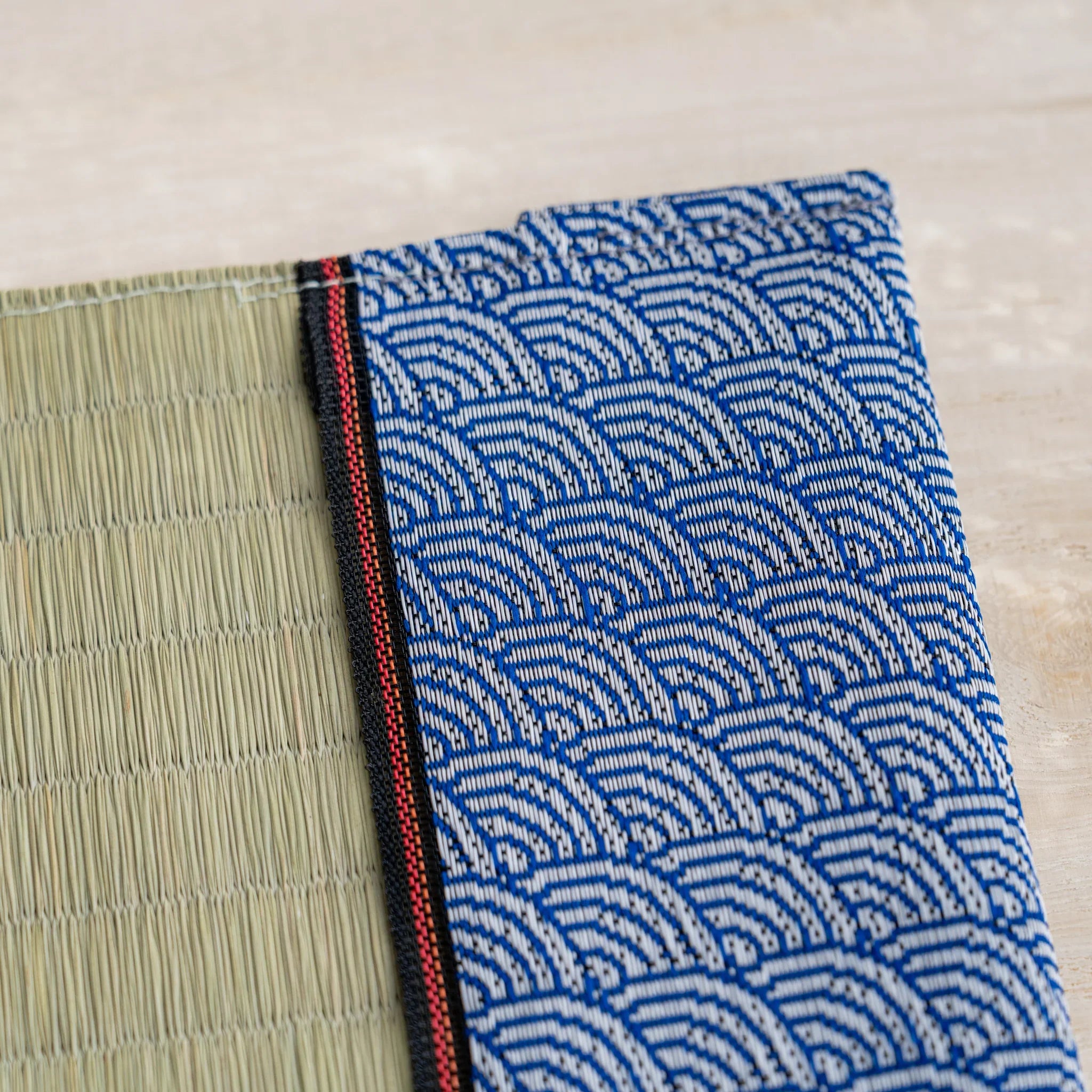 Close-up of blue and white wave pattern band with red and black striped trim next to green rush straw