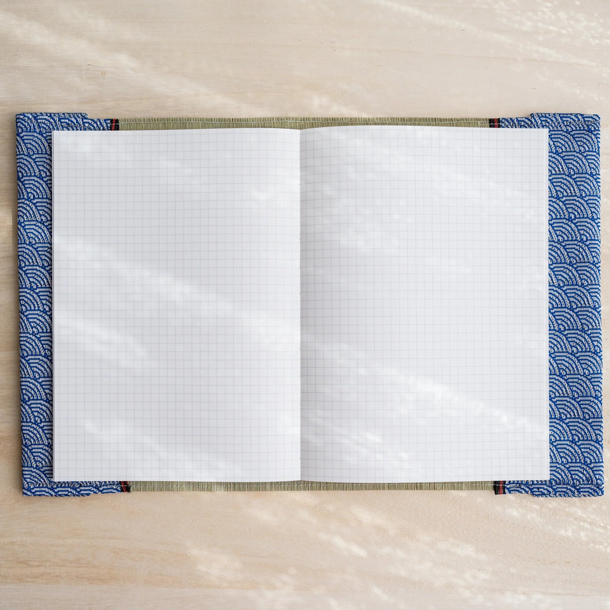 Tatami book cover open flat with white grid notebook pages, blue and white Japanese wave pattern fabric edges